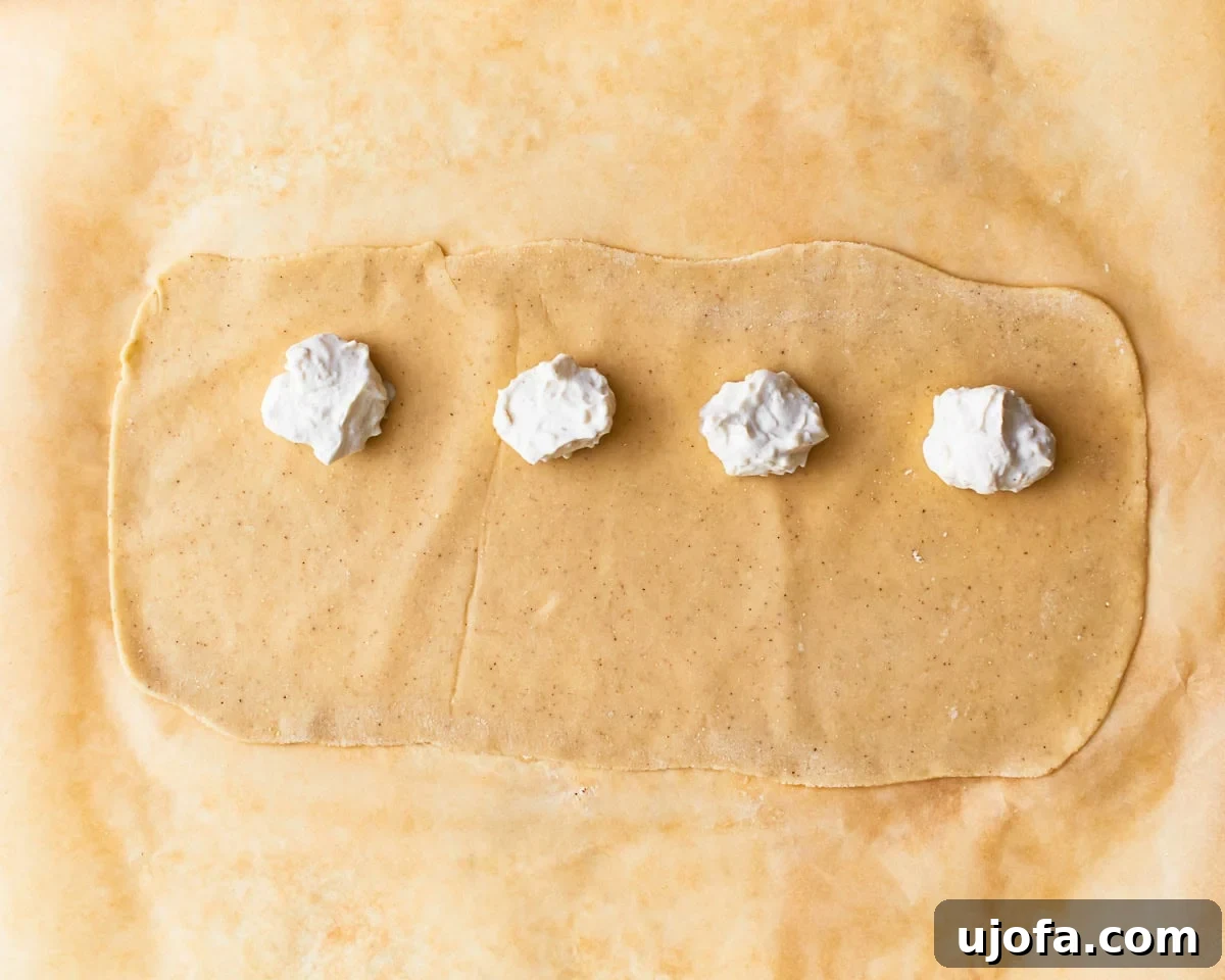 Spoonfuls of gluten-free ravioli filling on top of rolled out pasta dough.