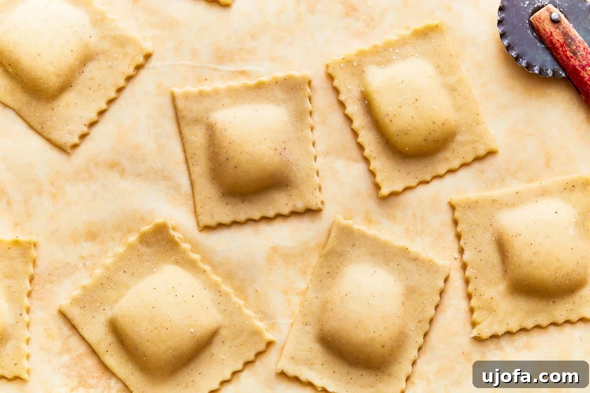 Shaped and filled gluten-free ravioli squares on parchment paper.
