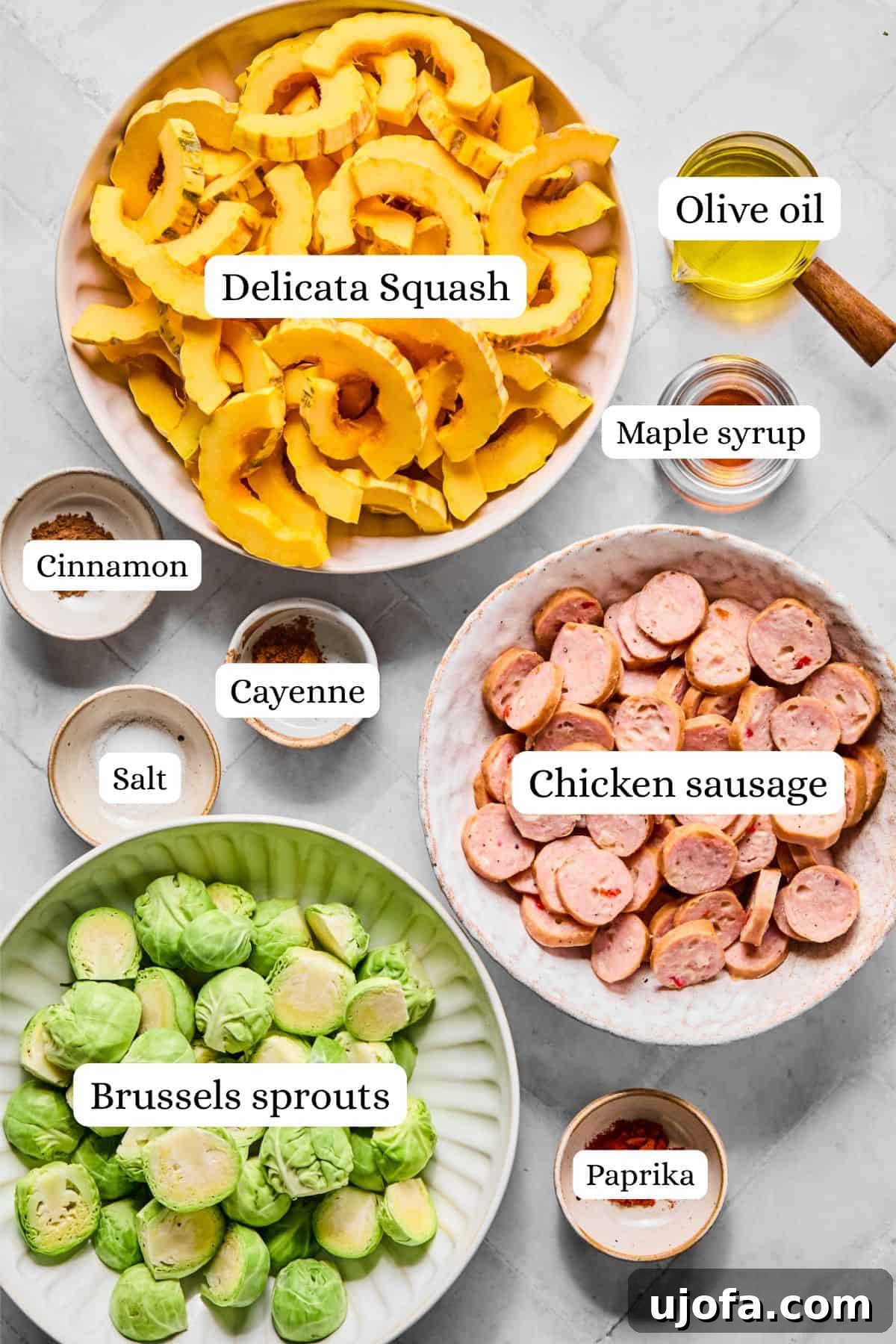 Sheet Pan Roasted Delicata Squash and Chicken Sausage 3 Ingredients for a harvest sheet pan dinner neatly arranged in nesting bowls: chicken sausage, delicata squash, Brussels sprouts, maple syrup, olive oil, and a spice blend.