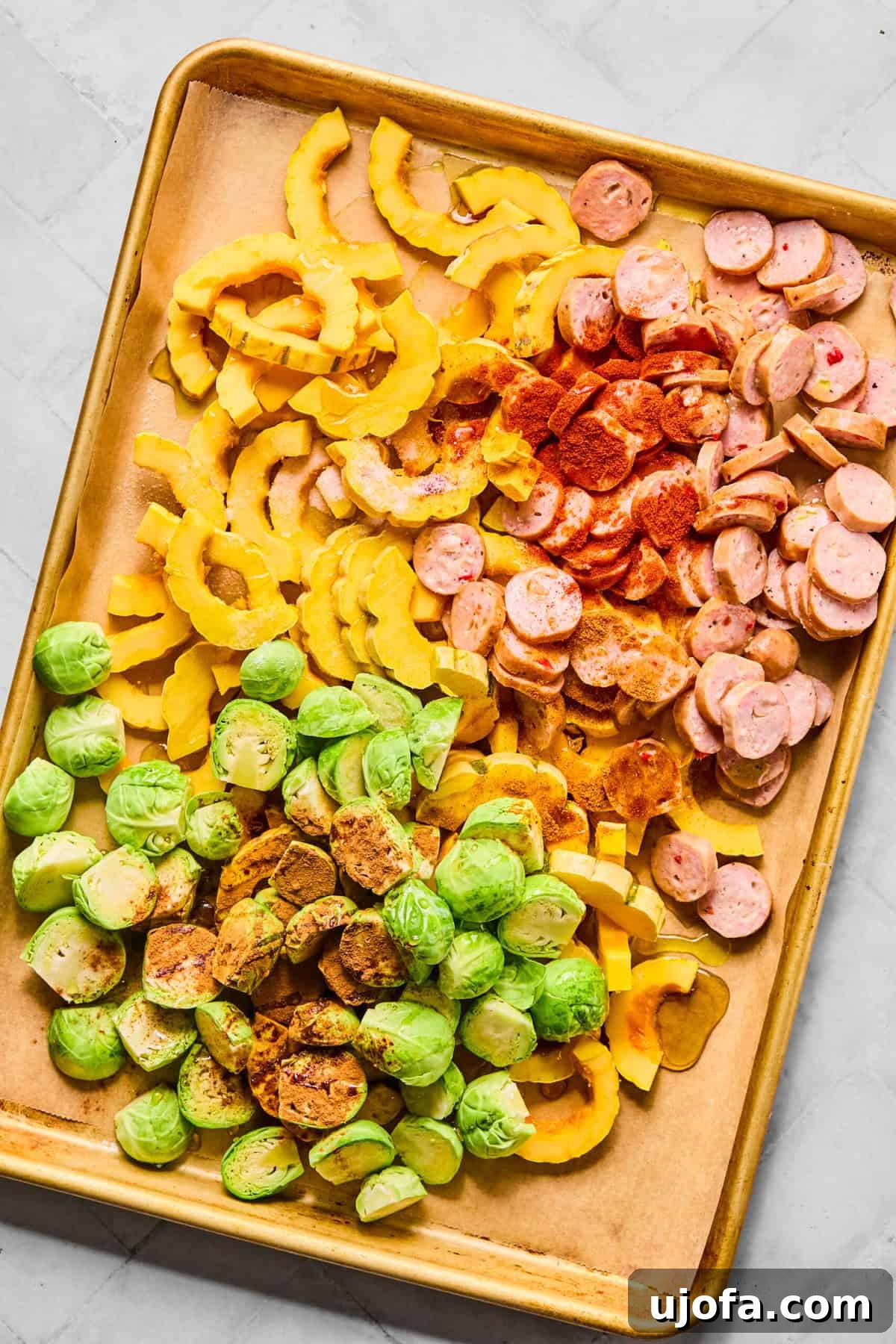Sheet Pan Roasted Delicata Squash and Chicken Sausage 5 The sheet pan with sausage, squash, and Brussels sprouts, drizzled with olive oil and maple syrup, ready for seasoning.