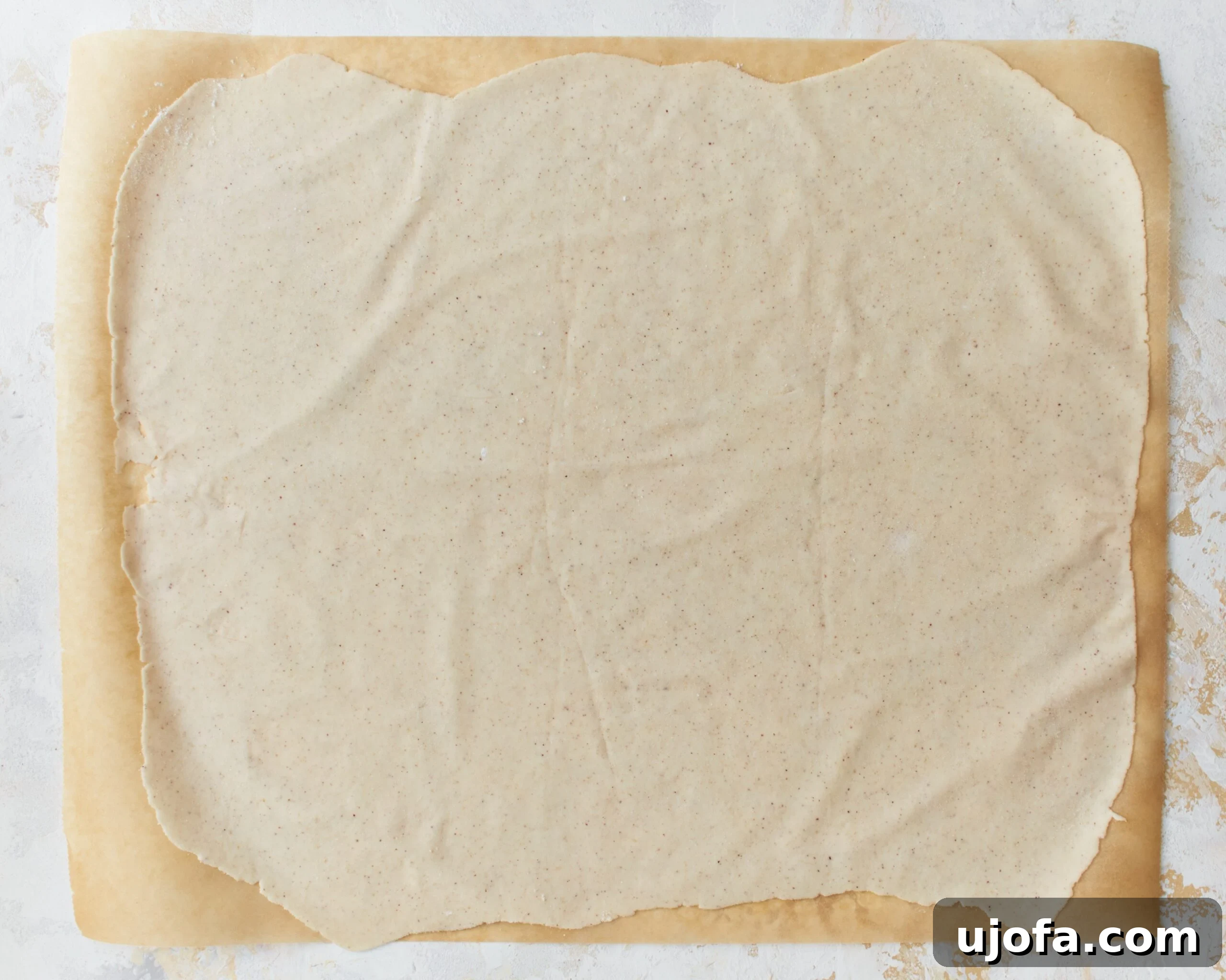 A sheet of gluten-free phyllo dough carefully rolled out to a thin, even consistency.