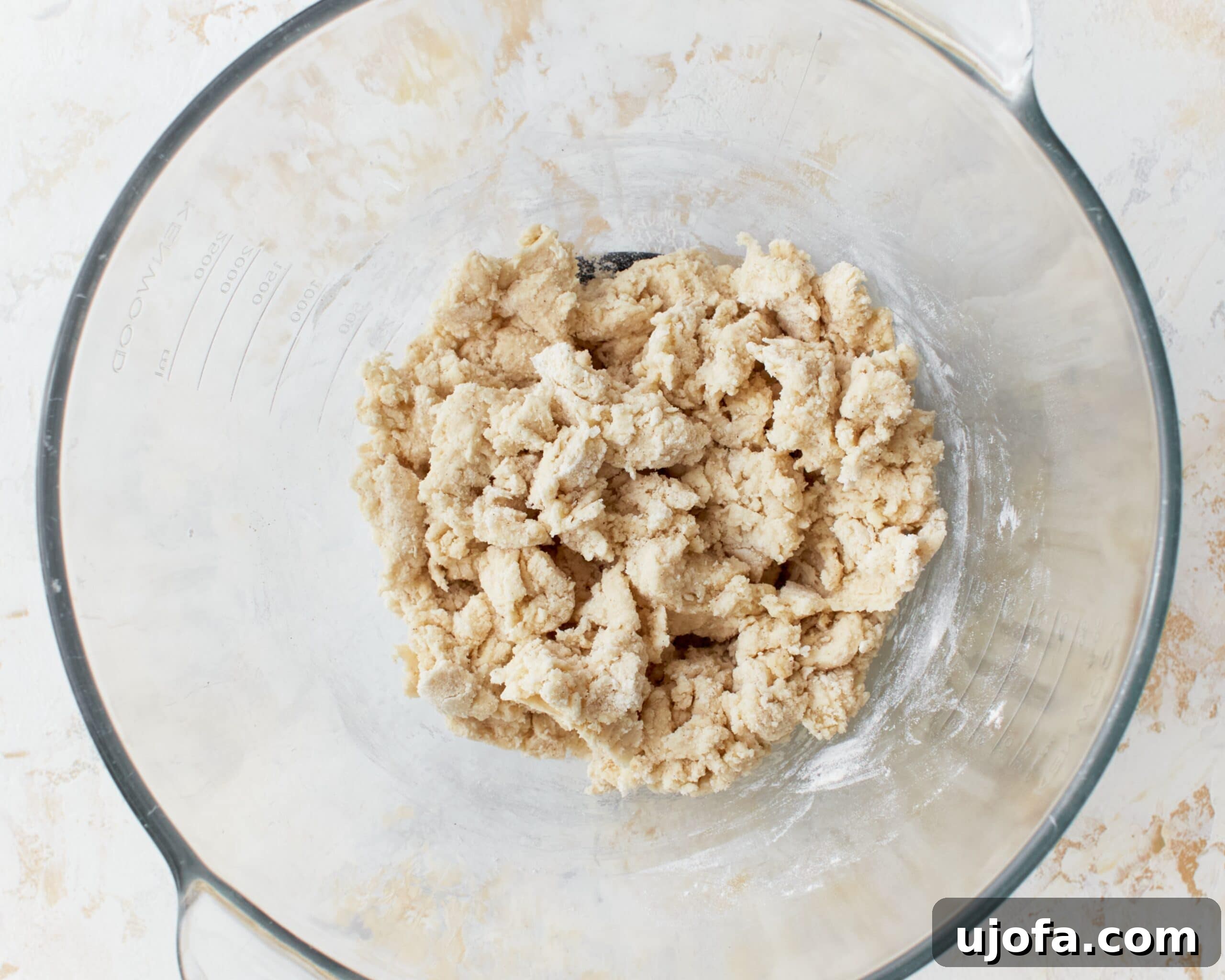 Shaggy gluten-free phyllo dough forming in a glass mixing bowl after wet ingredients have been added.