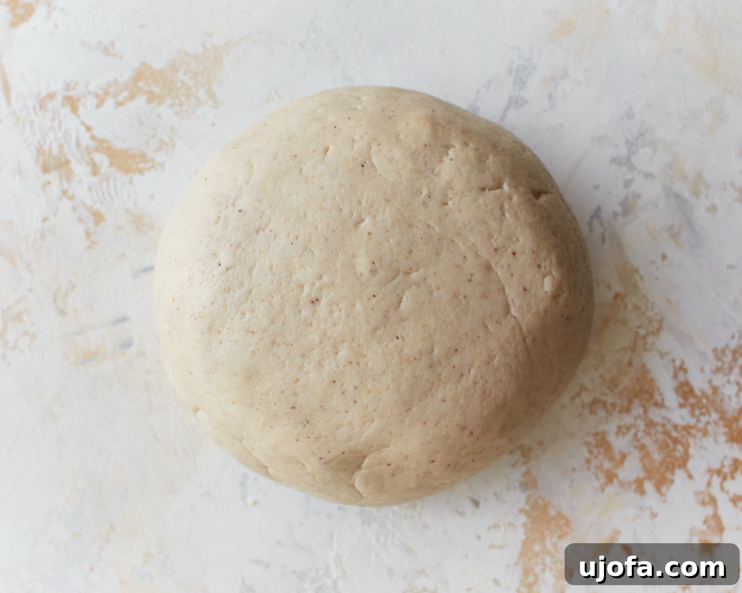 A smooth, pliable ball of gluten-free phyllo dough resting on a lightly floured surface.