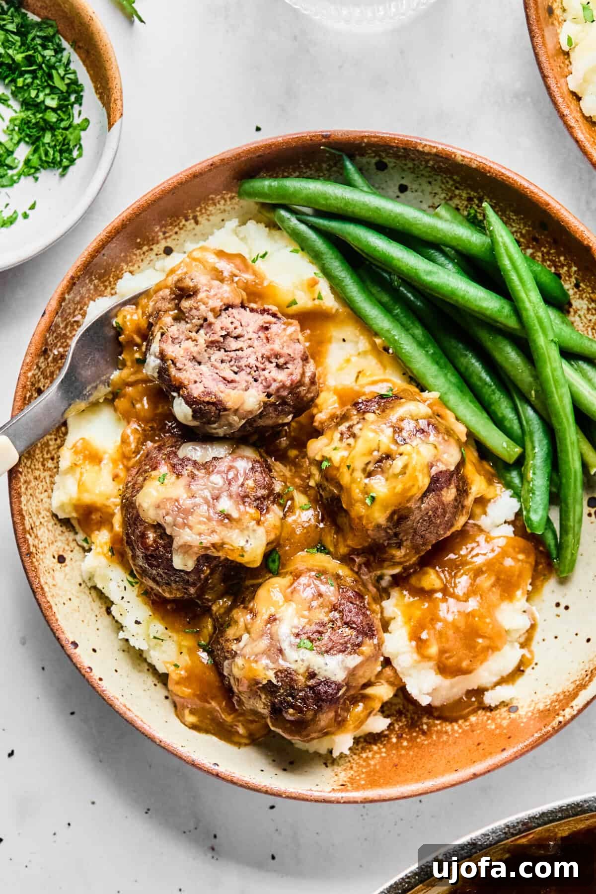 Savory French Onion Meatballs with Rich Gravy 2 A large skillet filled with French onion meatballs, bubbling in gravy and topped with melted Gruyère cheese, fresh from the oven.