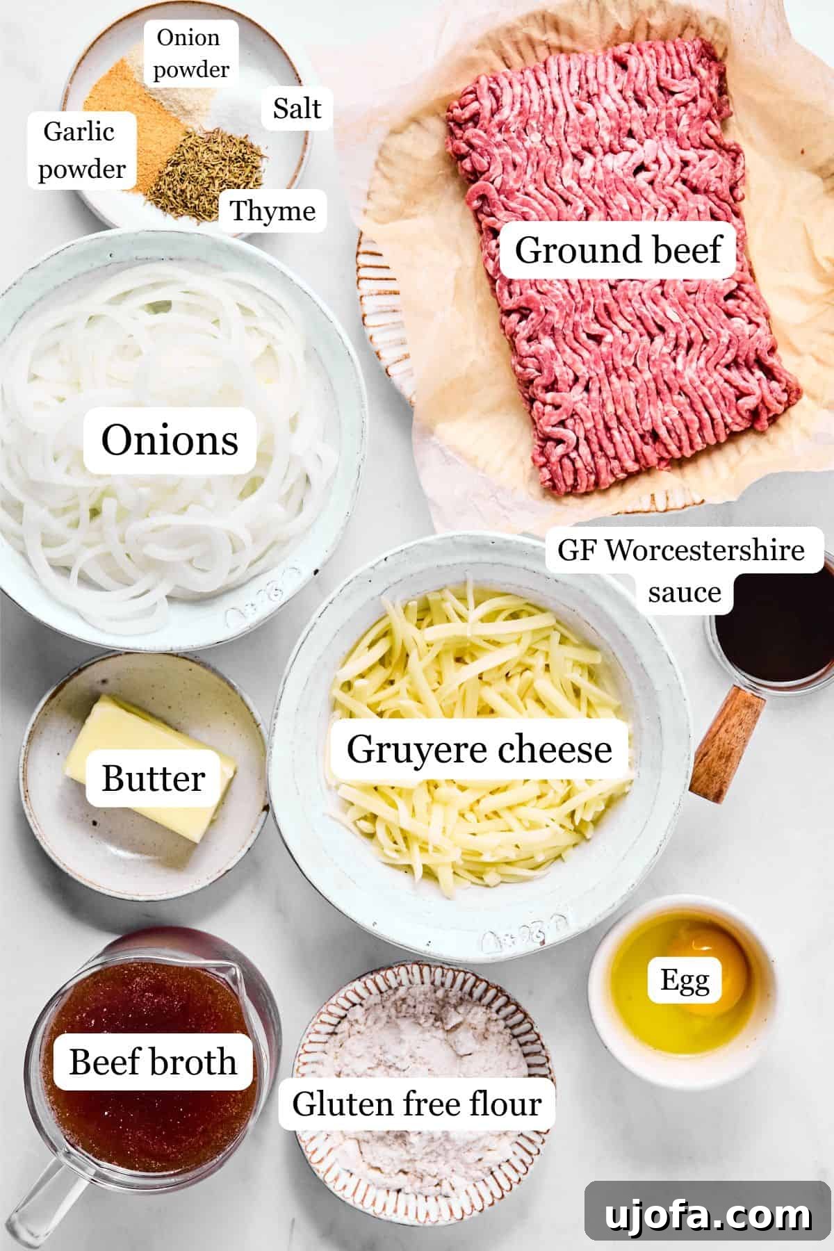Savory French Onion Meatballs with Rich Gravy 3 All the ingredients for French onion meatballs laid out on a white marble surface, including sliced onions, ground beef, butter, cheese, and various seasonings.