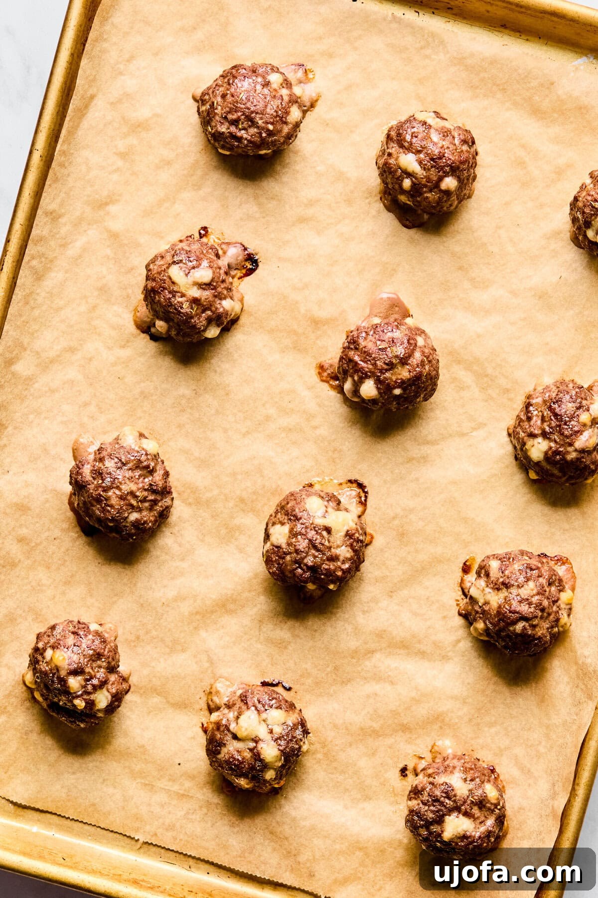 Savory French Onion Meatballs with Rich Gravy 7 Twelve neatly formed raw meatballs arranged on a parchment-lined baking sheet, ready for the oven.