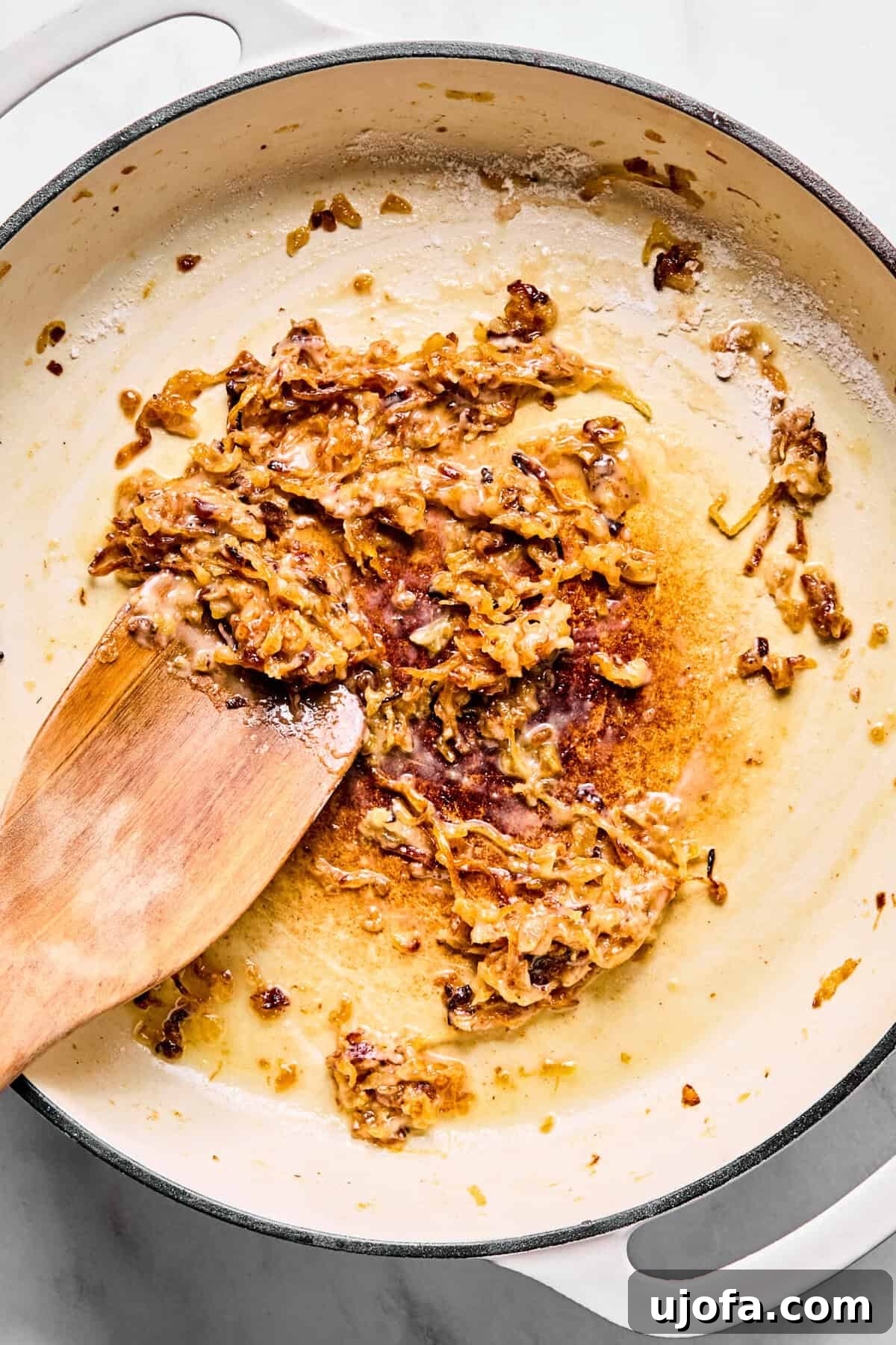 Savory French Onion Meatballs with Rich Gravy 8 Caramelized onions in a large oven-safe skillet with a dusting of gluten-free flour, being stirred to coat.