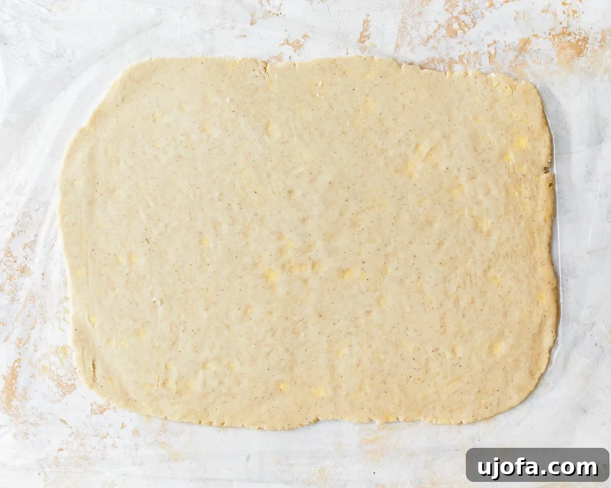 Chilled gluten-free puff pastry dough rolled out into a large, thin rectangle on a floured surface.
