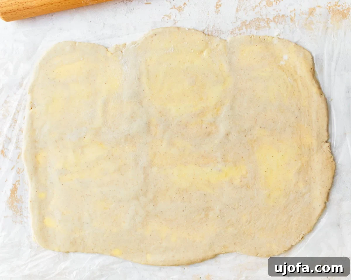 Rolled out puff pastry dough, rotated 90 degrees, showing visible flecks of butter throughout.
