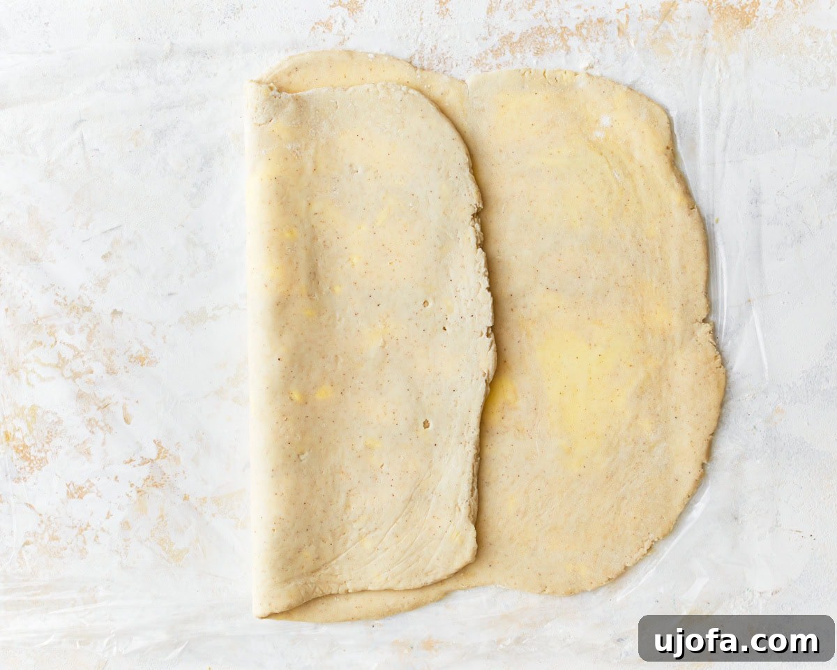 Gluten-free puff pastry dough partially folded, with one third brought over the middle section during the second turn.