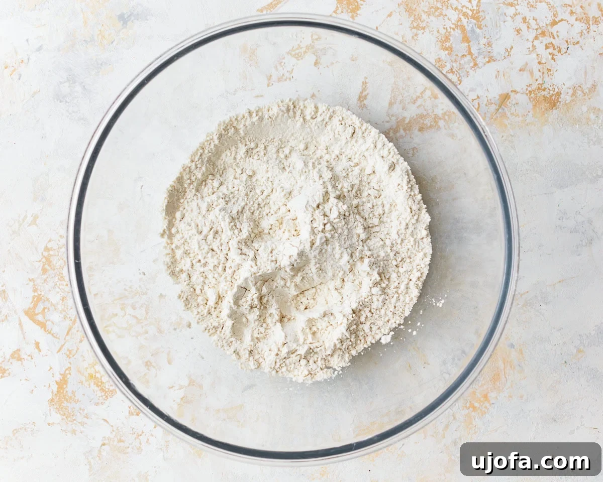 Dry ingredients for gluten-free puff pastry (flour, xanthan gum, sugar, salt) combined in a clear glass mixing bowl.