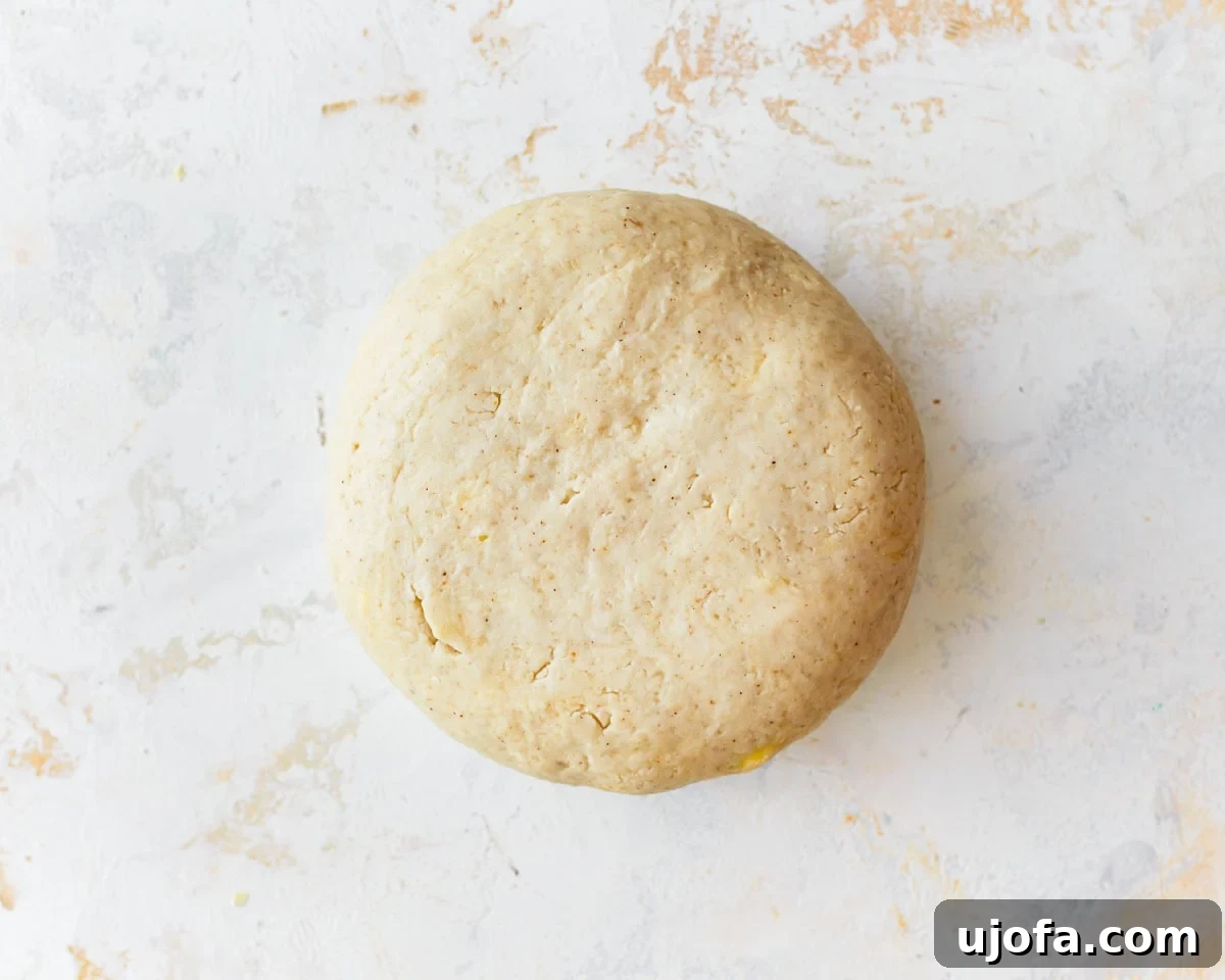 A smooth, round ball of gluten-free puff pastry dough on a lightly floured surface.