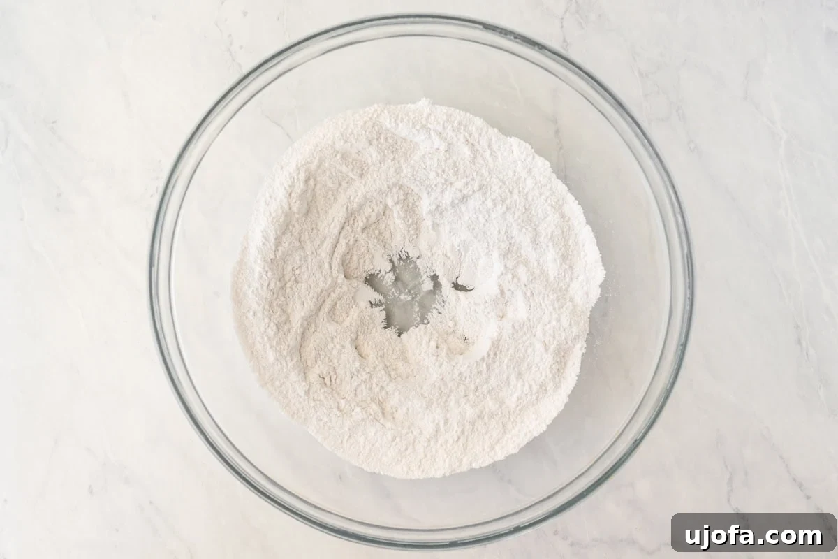 Crafting Gluten-Free Wonton Delights 6 A glass mixing bowl holds dry ingredients for gluten-free wonton wrappers: glutinous rice flour, GF flour blend, sea salt, and xanthan gum, whisked together.