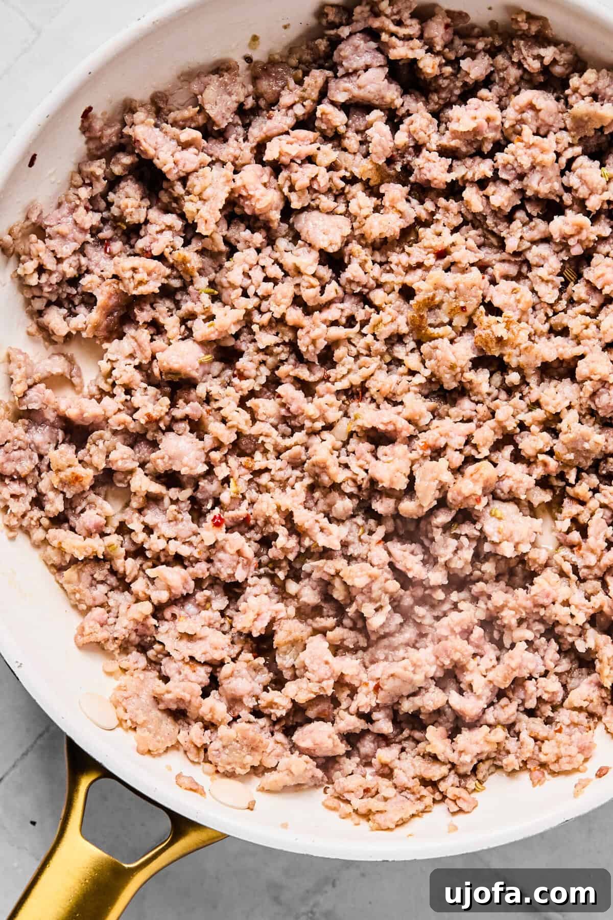 Browning Italian sausage in a skillet over medium heat, breaking it into small, even pieces as it cooks.