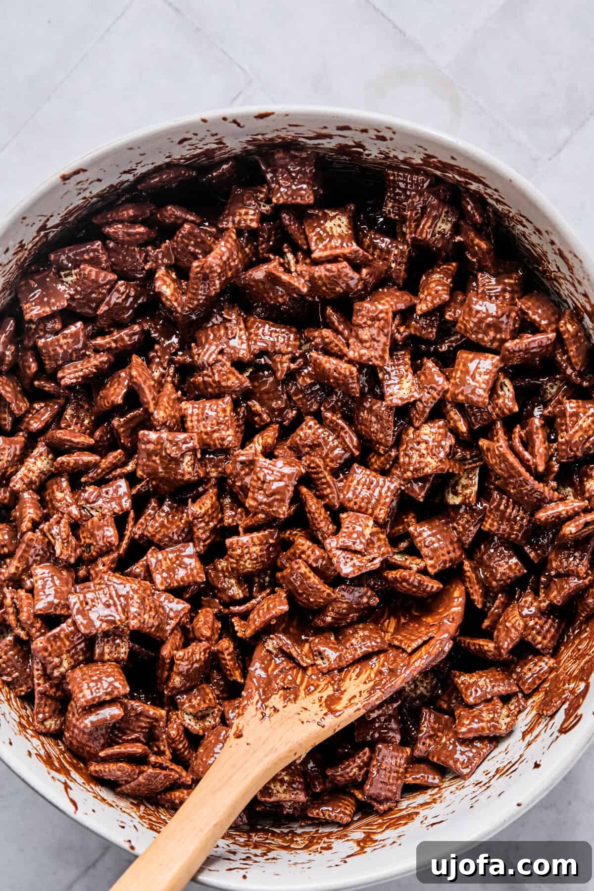 Chex cereal gently tossed in a bowl until evenly coated with the melted chocolate peanut butter mixture.