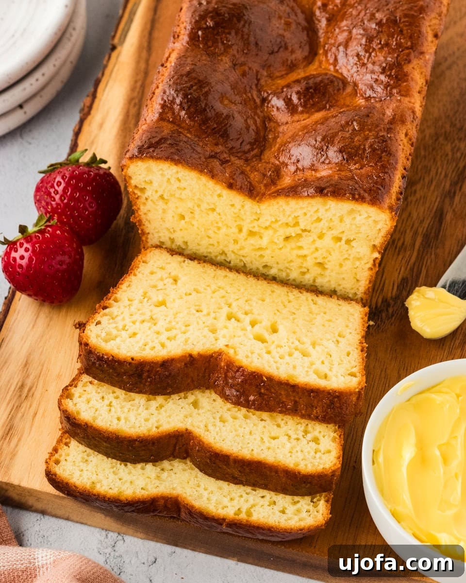 Overhead view of a sliced gluten-free brioche loaf on a wooden chopping board, showcasing its tender crumb and golden crust.