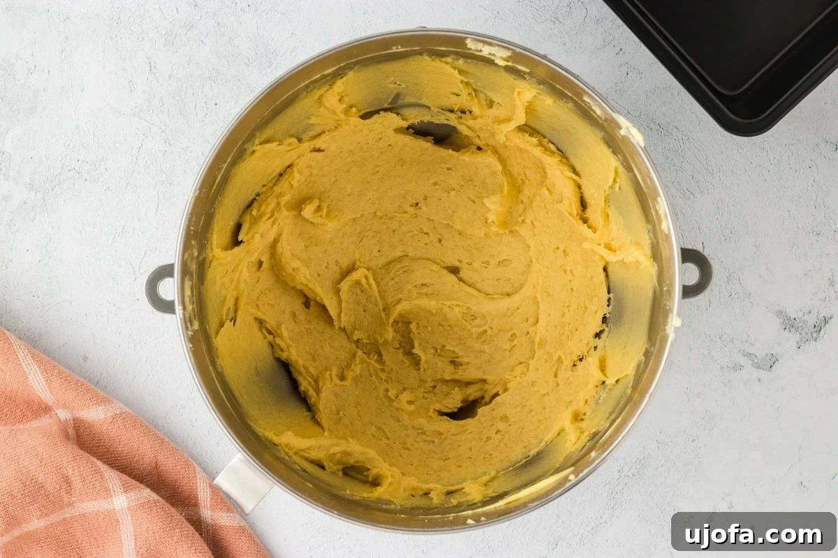 Gluten-free brioche batter being gently mixed with warm milk in a stand mixer.