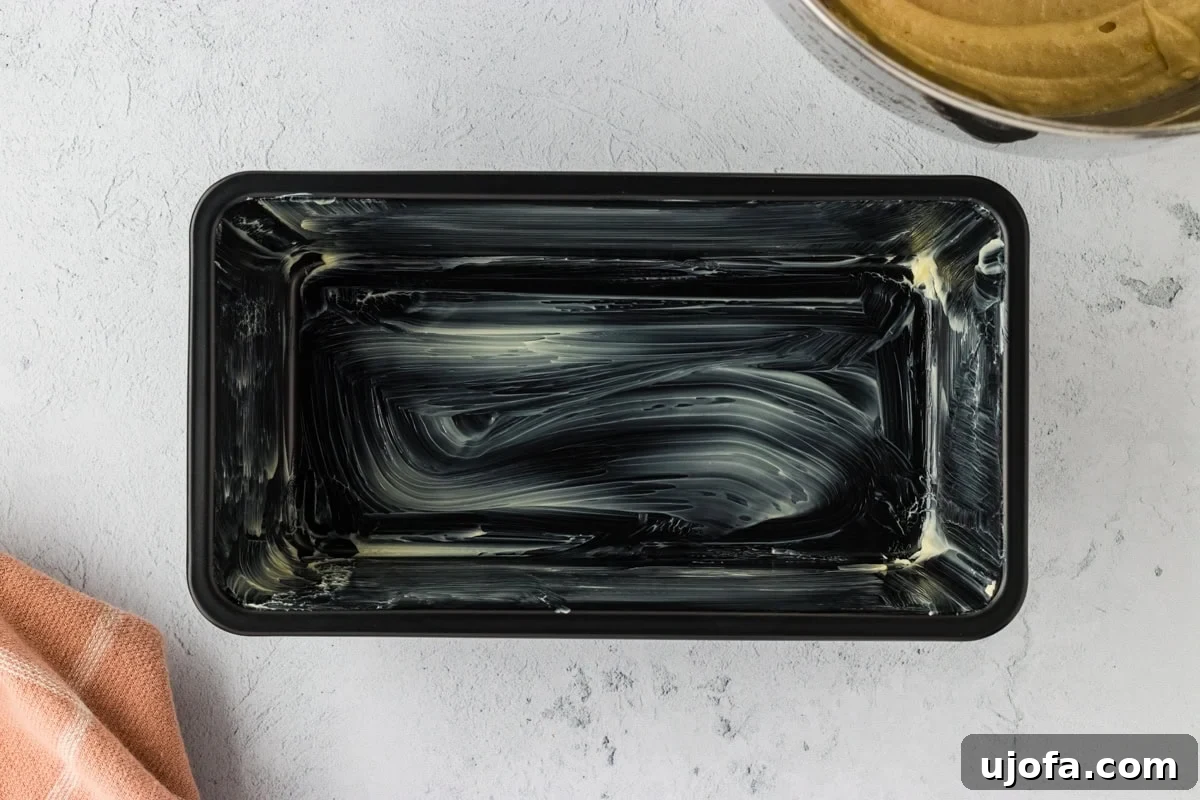 A loaf pan meticulously greased with butter, preparing it for the brioche dough.