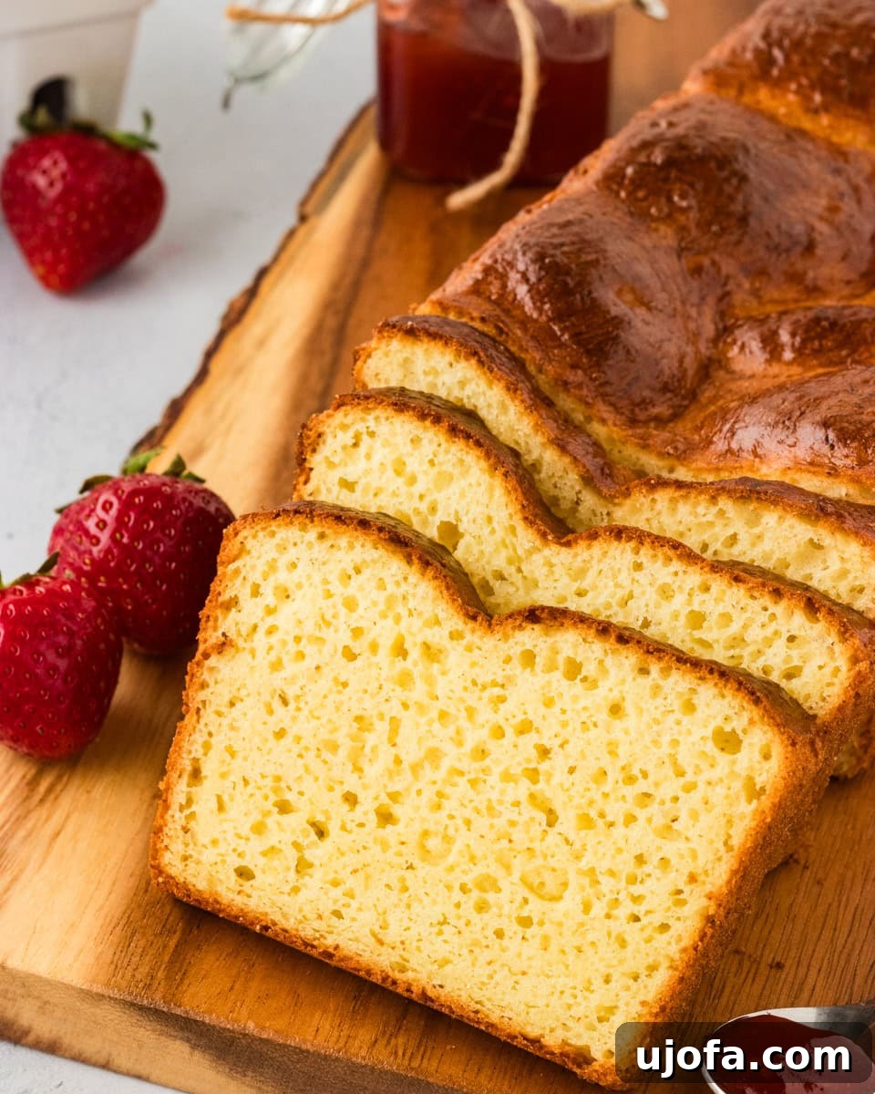 Slices of golden-brown gluten-free brioche bread neatly stacked on a wooden chopping board, highlighting its appealing texture.