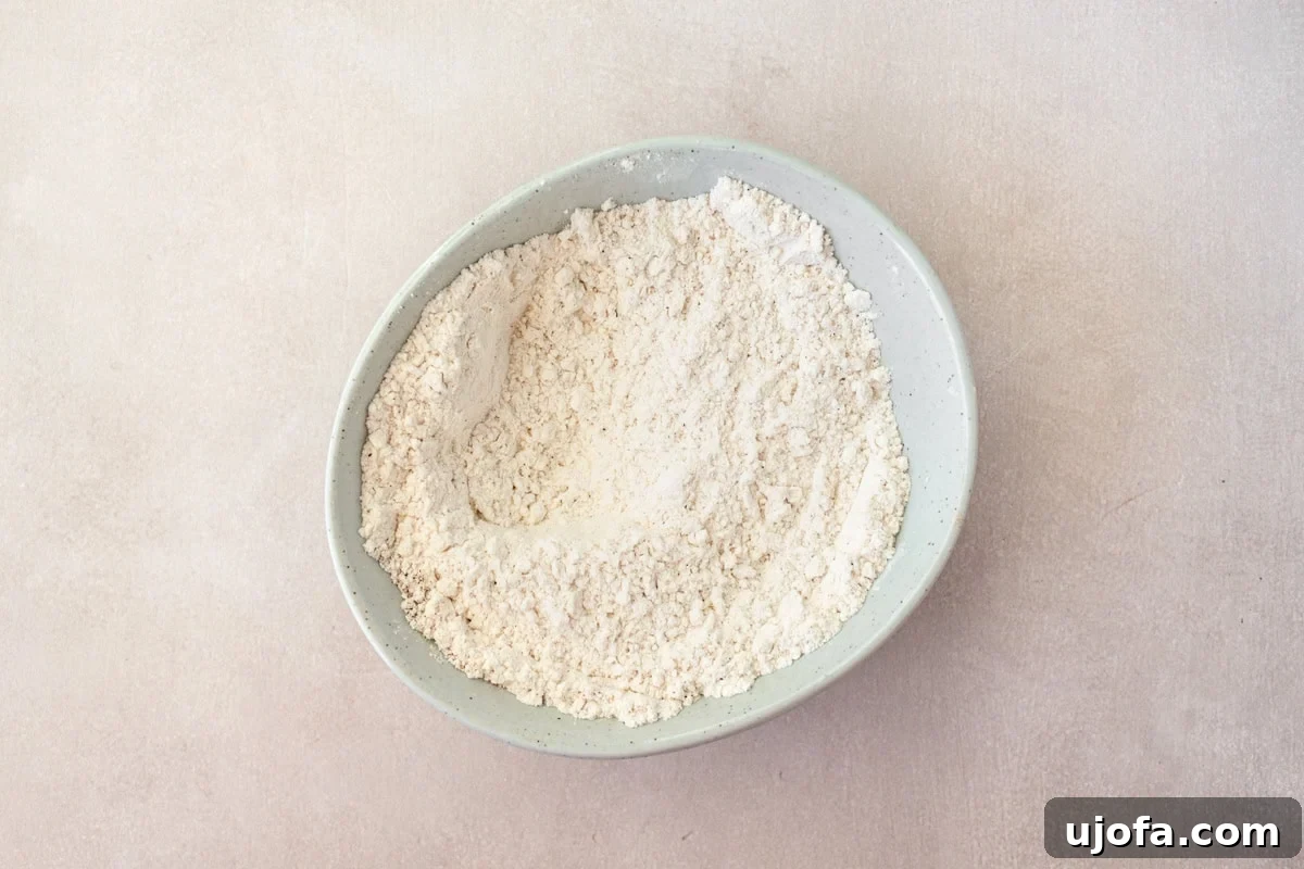 A bowl containing the dry ingredients for gluten-free fried onions: gluten-free flour, salt, pepper, garlic powder, and smoked paprika.