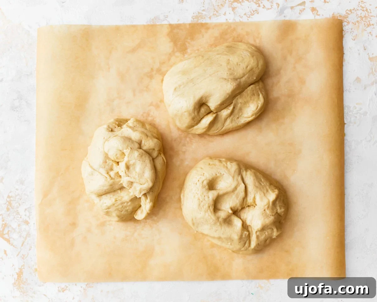 Gluten-free challah bread divided into three portions on a piece of parchment paper.