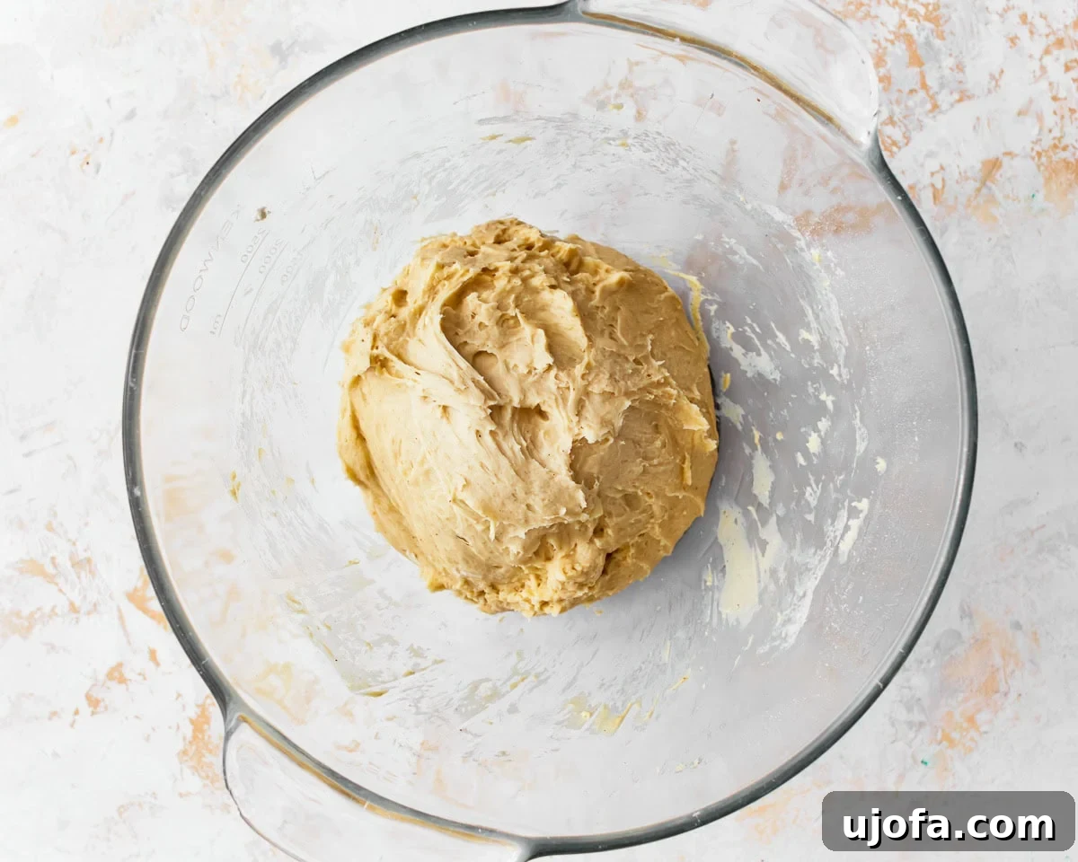 A sticky dough for gluten-free challah bread in a glass mixing bowl.