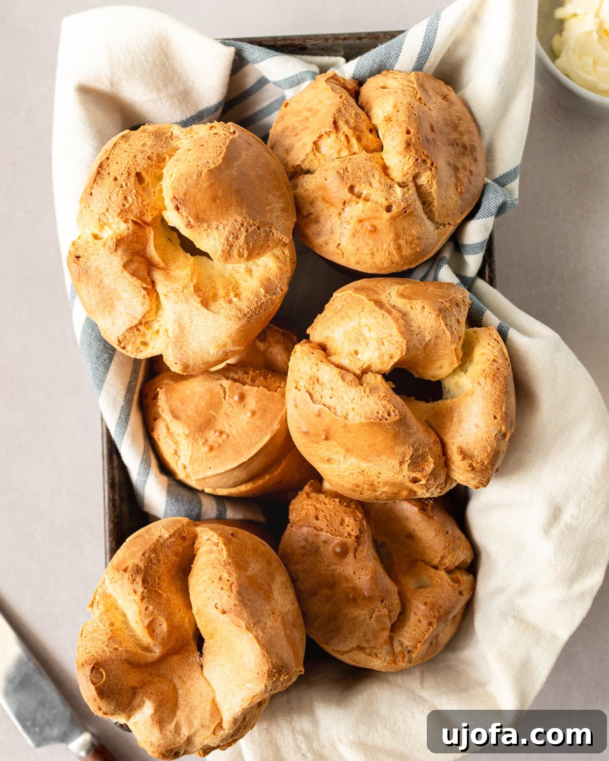 Overhead view of perfectly baked gluten-free popovers in a towel-lined baking pan, ready to be served.