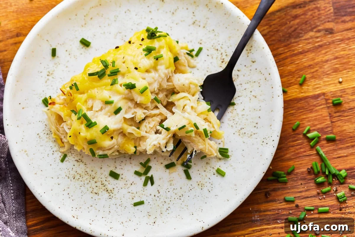 Yalancı Peynirli Patates 4 Overhead view of a plate of dairy-free cheesy potatoes with a fork.