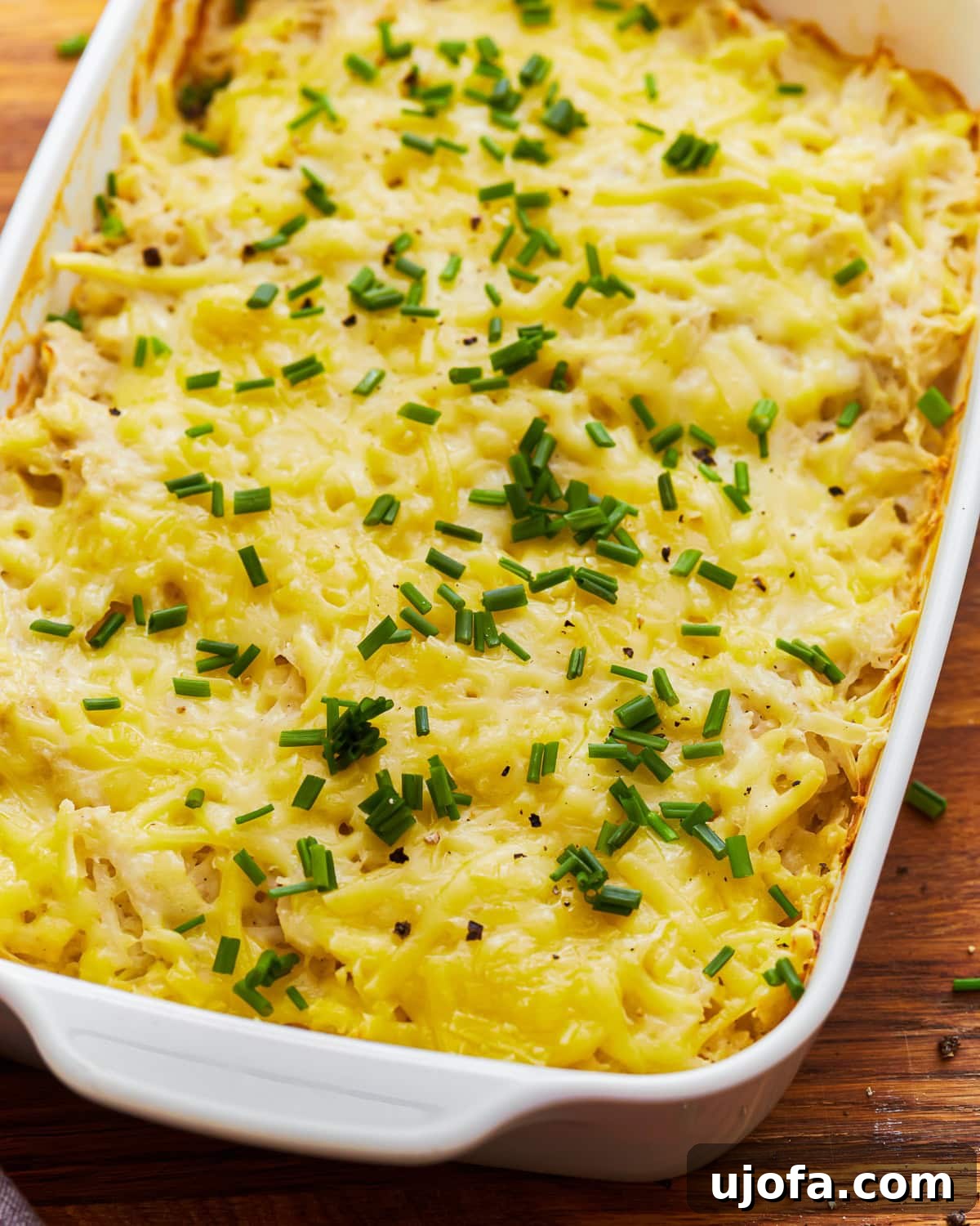 Yalancı Peynirli Patates 5 Overhead view of dairy-free cheesy potatoes in a baking dish, topped with fresh parsley.