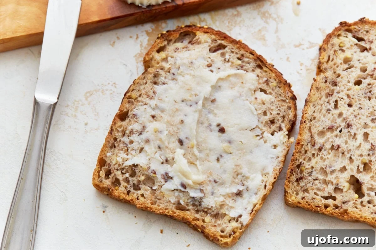 A perfectly toasted piece of bread, generously slathered with homemade vegan butter, ready to be enjoyed as a simple yet satisfying treat.
