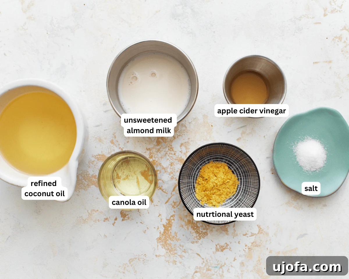 A close-up view of the simple ingredients needed to make homemade vegan butter, including jars of coconut oil, canola oil, and a bottle of almond milk, neatly arranged on a kitchen counter.