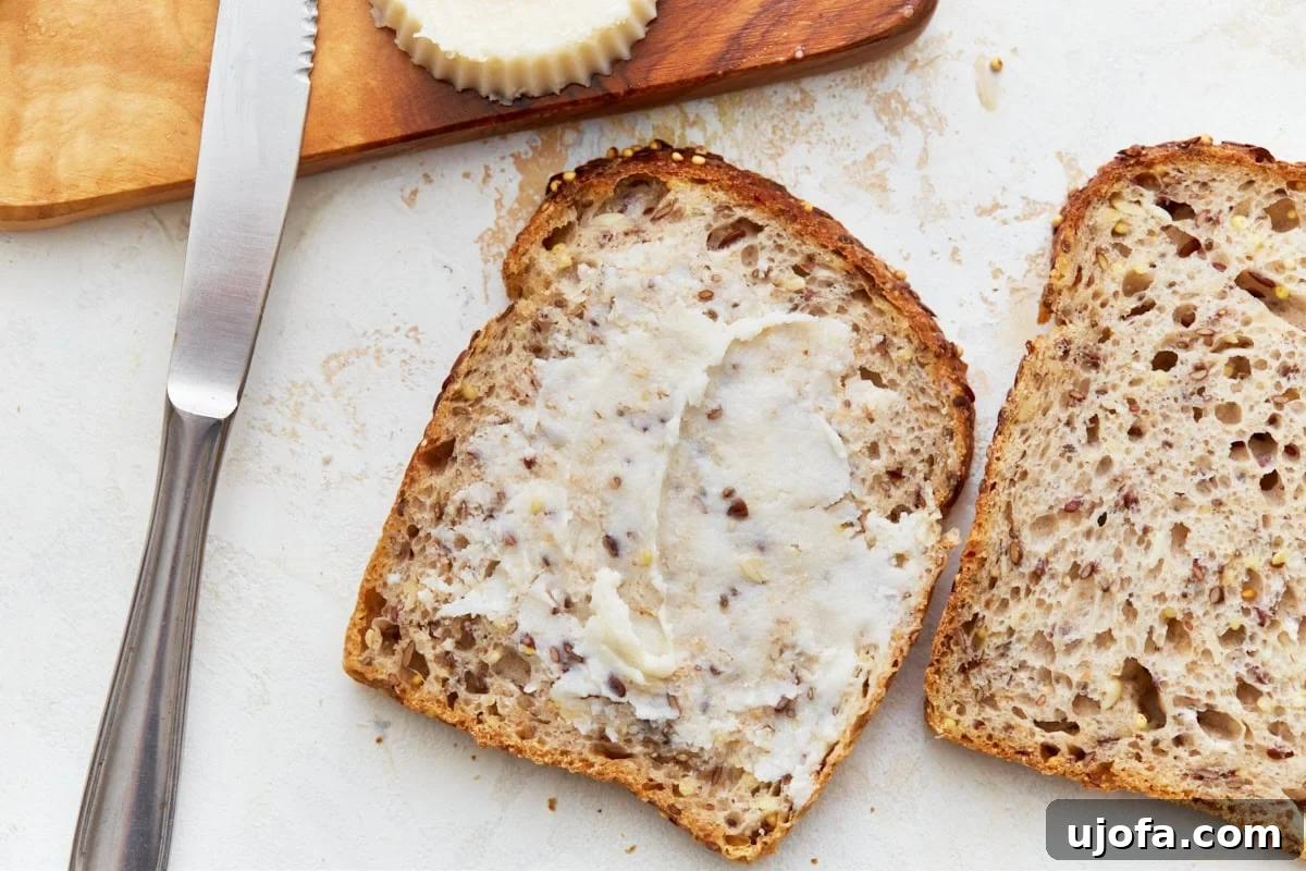 A side-by-side comparison of one piece of unbuttered toast next to another generously slathered with homemade vegan butter, showcasing the smooth spreadability.