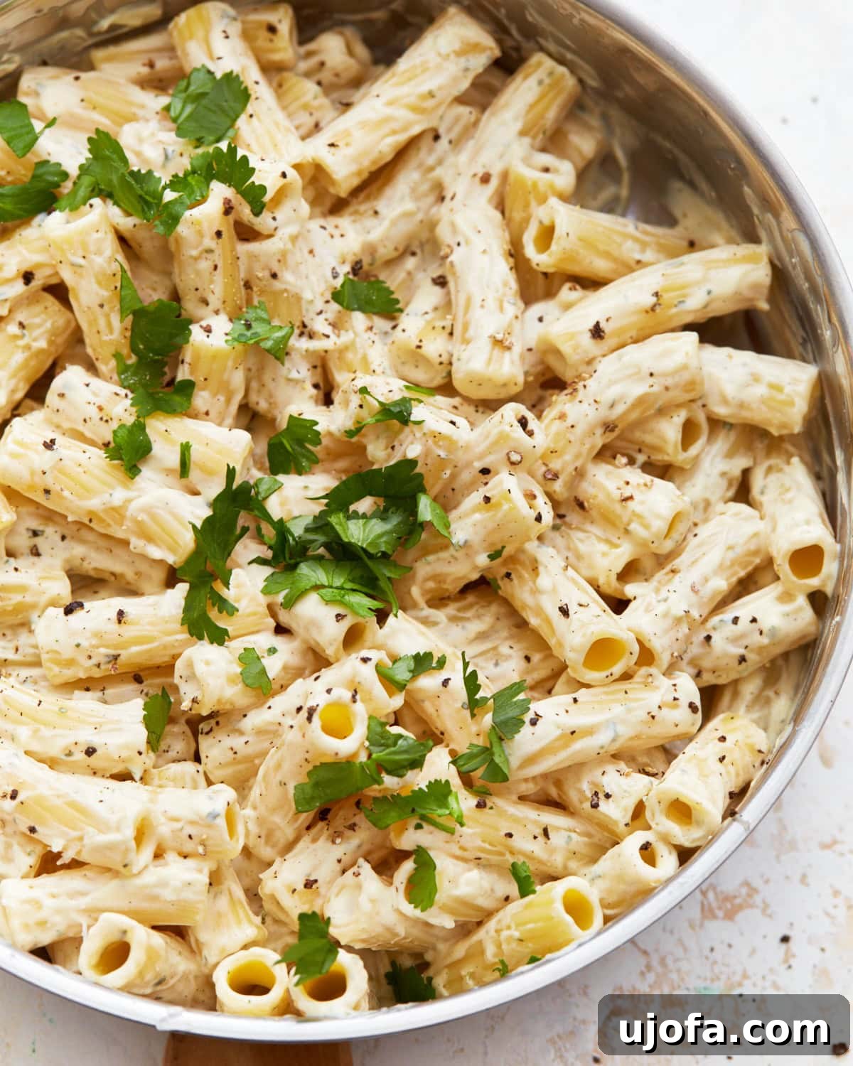 Decadent Gluten Free Boursin Pasta 2 A close up shot of gluten-free Boursin cheese pasta in a white serving bowl with parsley garnish