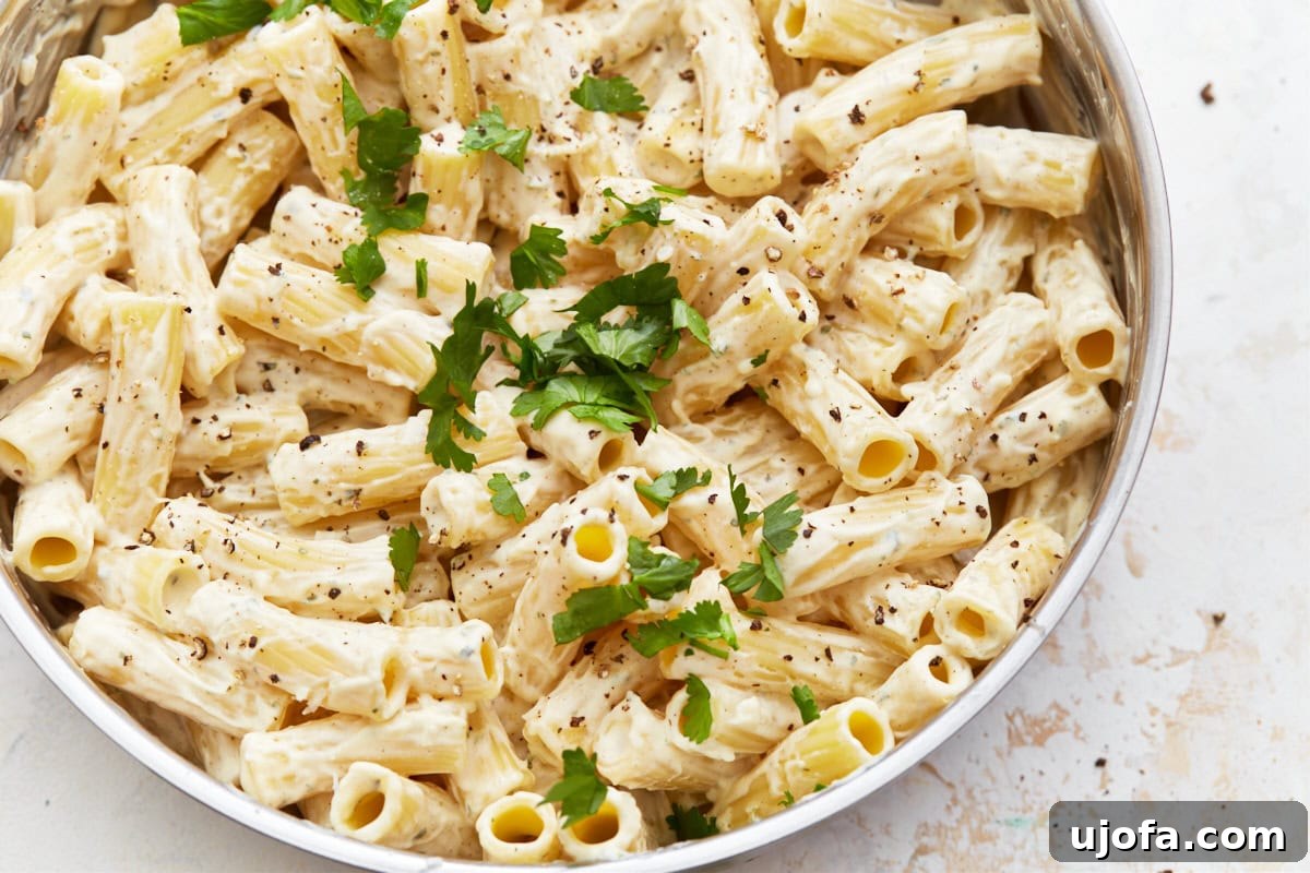Decadent Gluten Free Boursin Pasta 6 A close up shot of gluten-free Boursin cheese pasta in a white serving bowl with parsley garnish