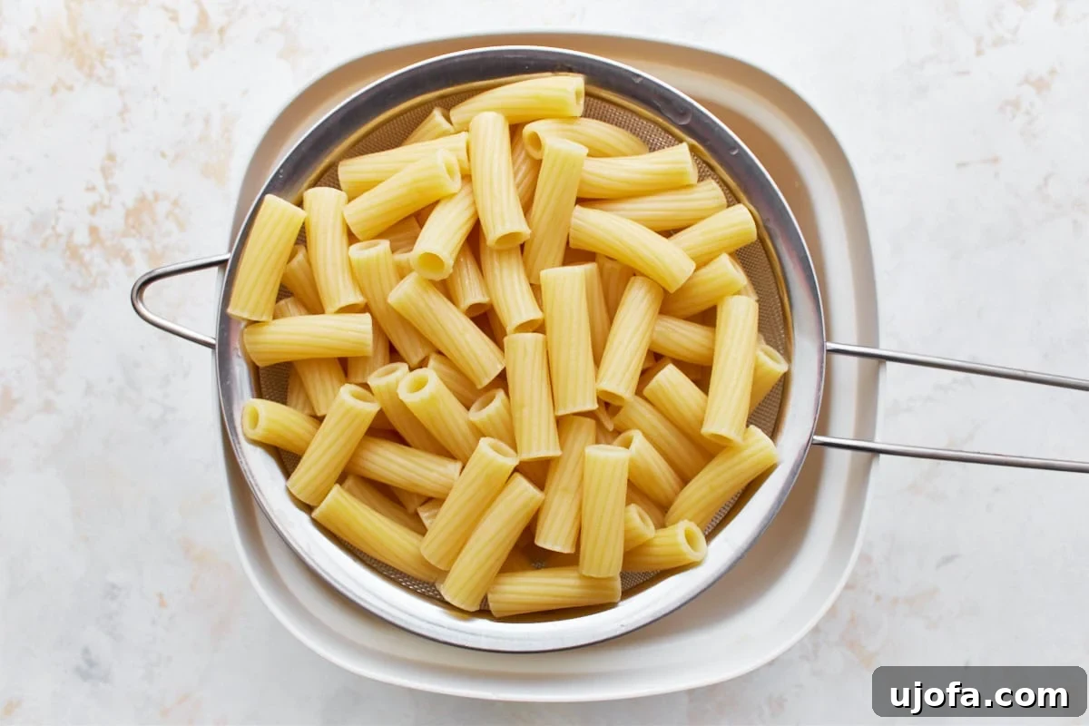 Decadent Gluten Free Boursin Pasta 7 An overhead view of cooked pasta in a colander over a white bowl