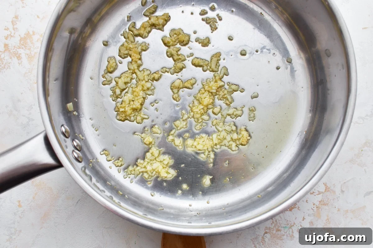 Decadent Gluten Free Boursin Pasta 8 An overhead view of a silver pot with minced garlic at the bottom