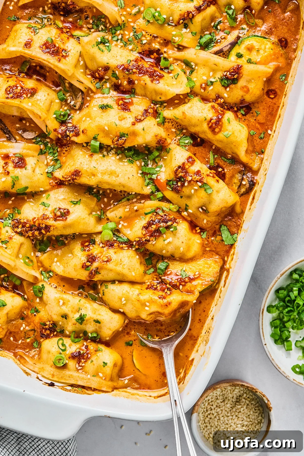 Gluten Free dumplings baked in a casserole dish with a vibrant red sauce, generously topped with fresh cilantro and vibrant green onions.