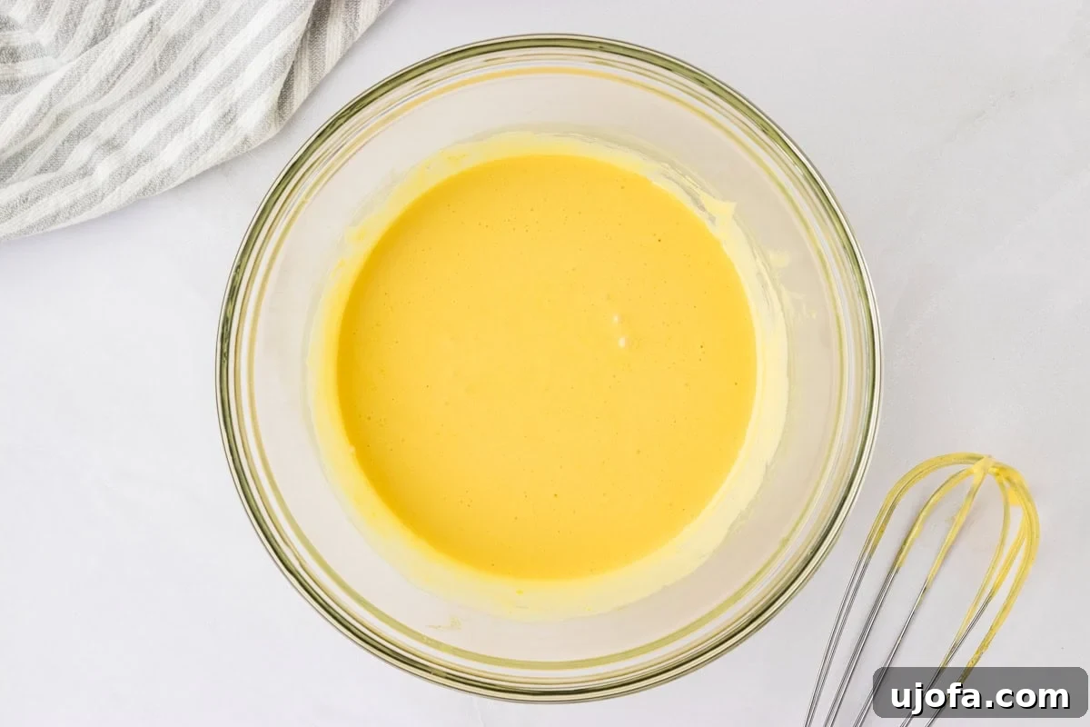 whipped egg yolk mixture in glass bowl on counter with mixer next to bowl