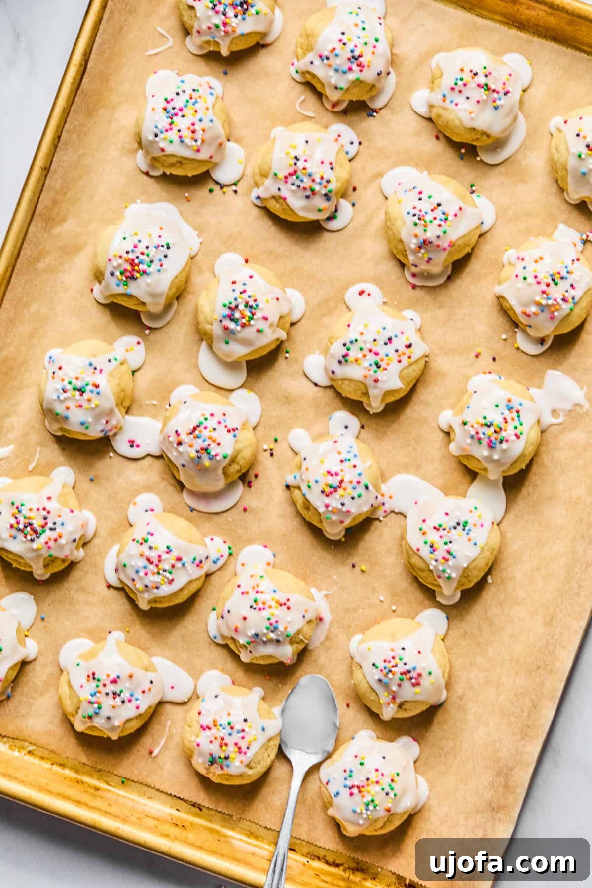 Sweet Traditions: Gluten-Free Italian Wedding Cookies 11 Gluten free Italian wedding cookies with almond glaze and rainbow sprinkles on a parchment lined baking sheet.