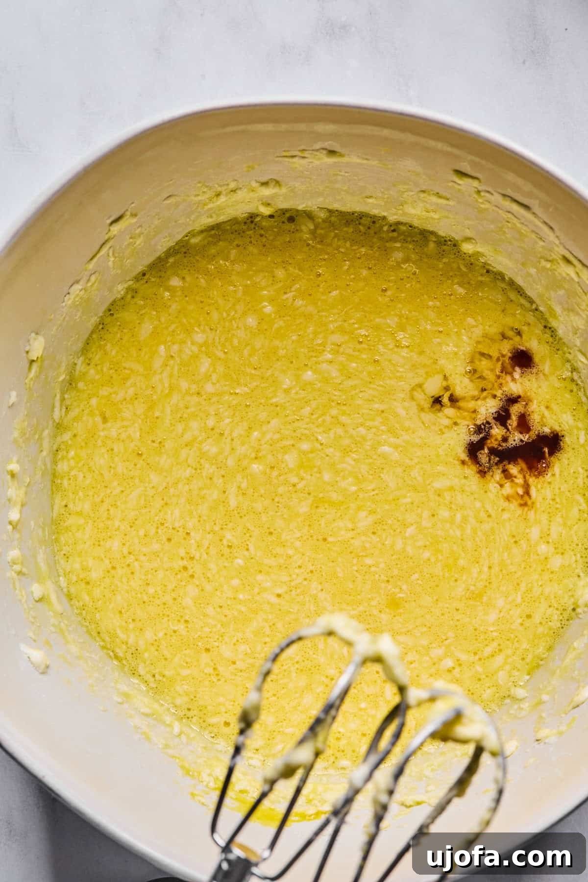 Sweet Traditions: Gluten-Free Italian Wedding Cookies 6 Eggs mixed into the batter in a large mixing bowl, with vanilla and almond extracts added and blended until smooth.