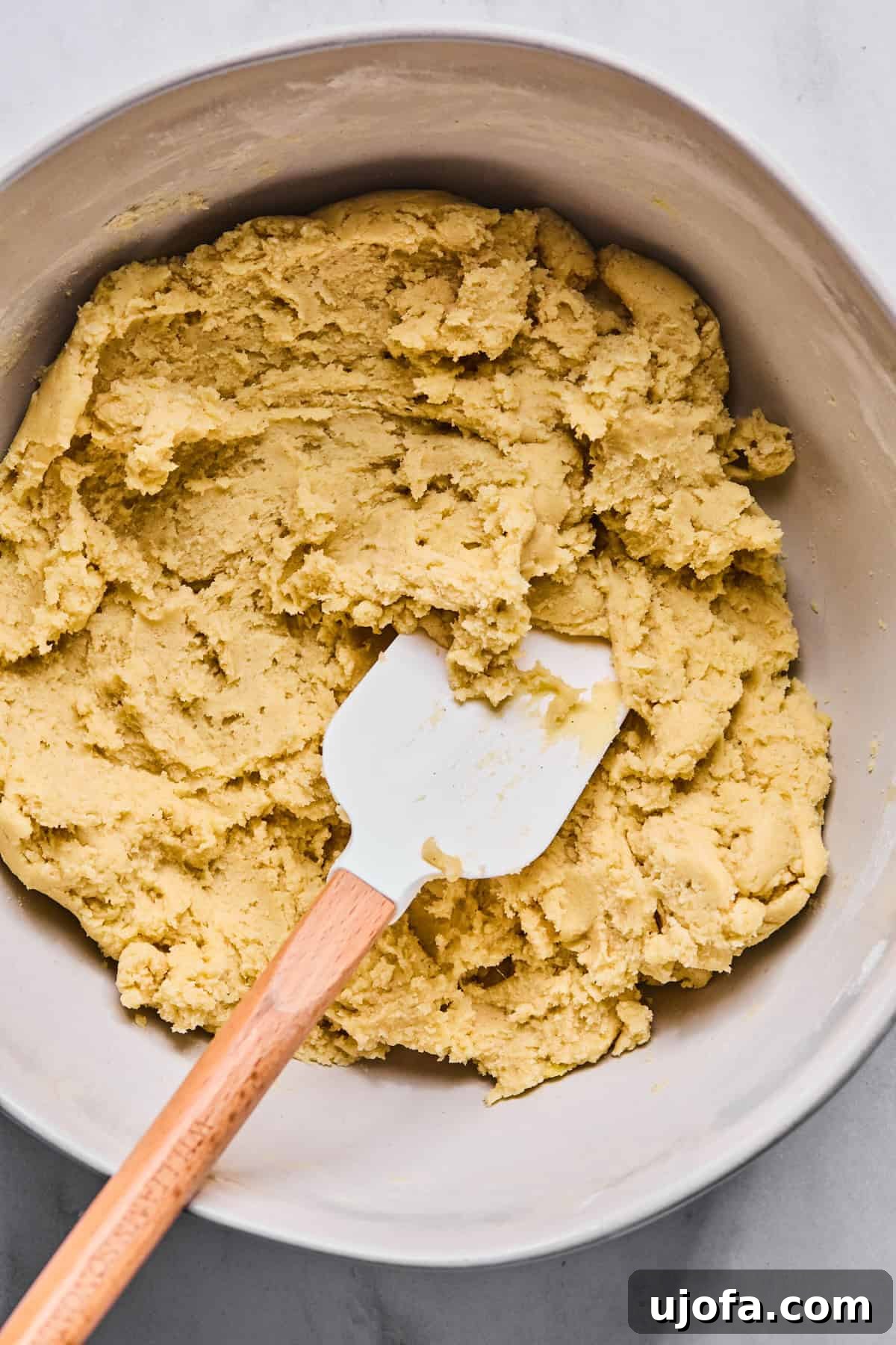 Sweet Traditions: Gluten-Free Italian Wedding Cookies 7 Gluten free Italian wedding cookie dough in a large bowl with a spatula resting in it.