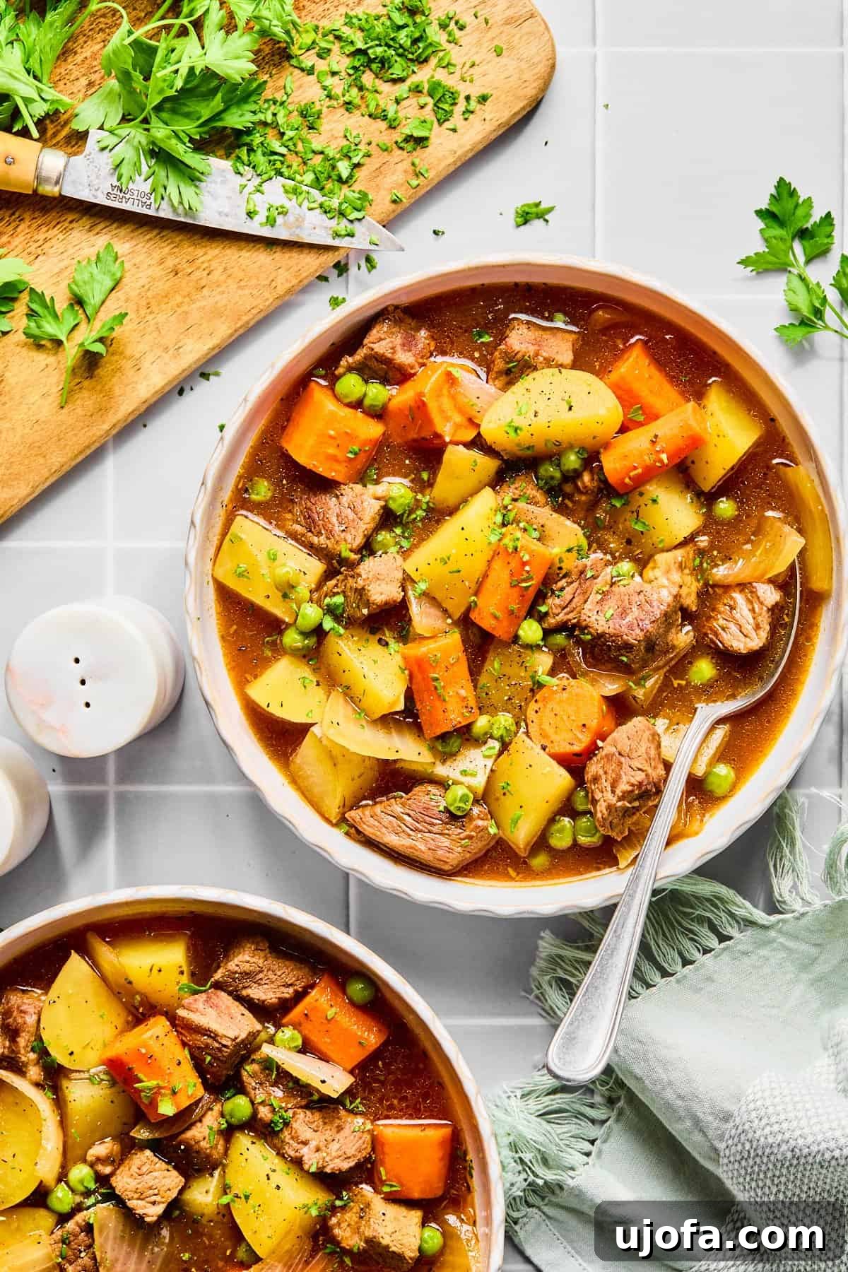 Set It and Forget It Hearty Beef Stew 11 Two cozy bowls of slow cooker beef stew, garnished with fresh herbs, resting on a light gray countertop, ready for a comforting meal.