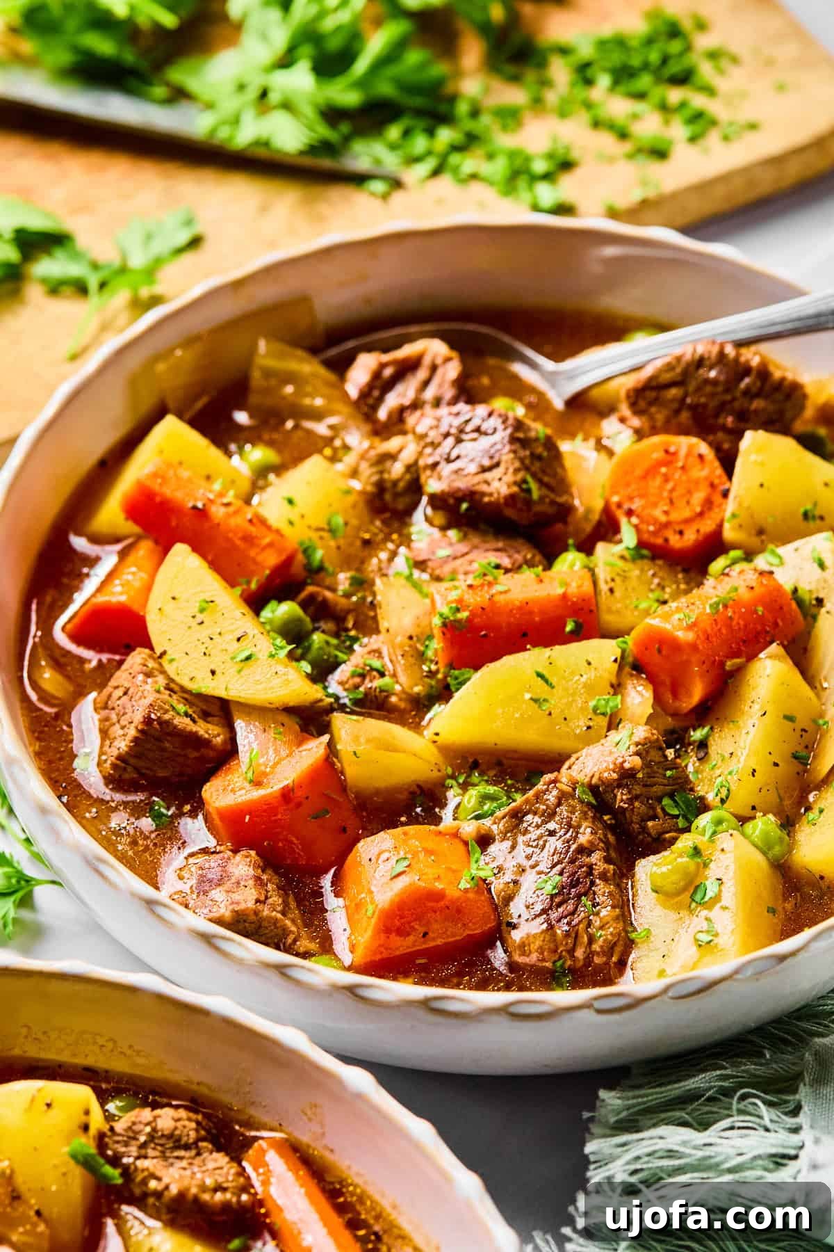 Set It and Forget It Hearty Beef Stew 12 A close-up shot of a bowl of slow cooker beef stew, showcasing the rich, thick broth, tender beef, and colorful vegetables, with a spoon taking a scoop.