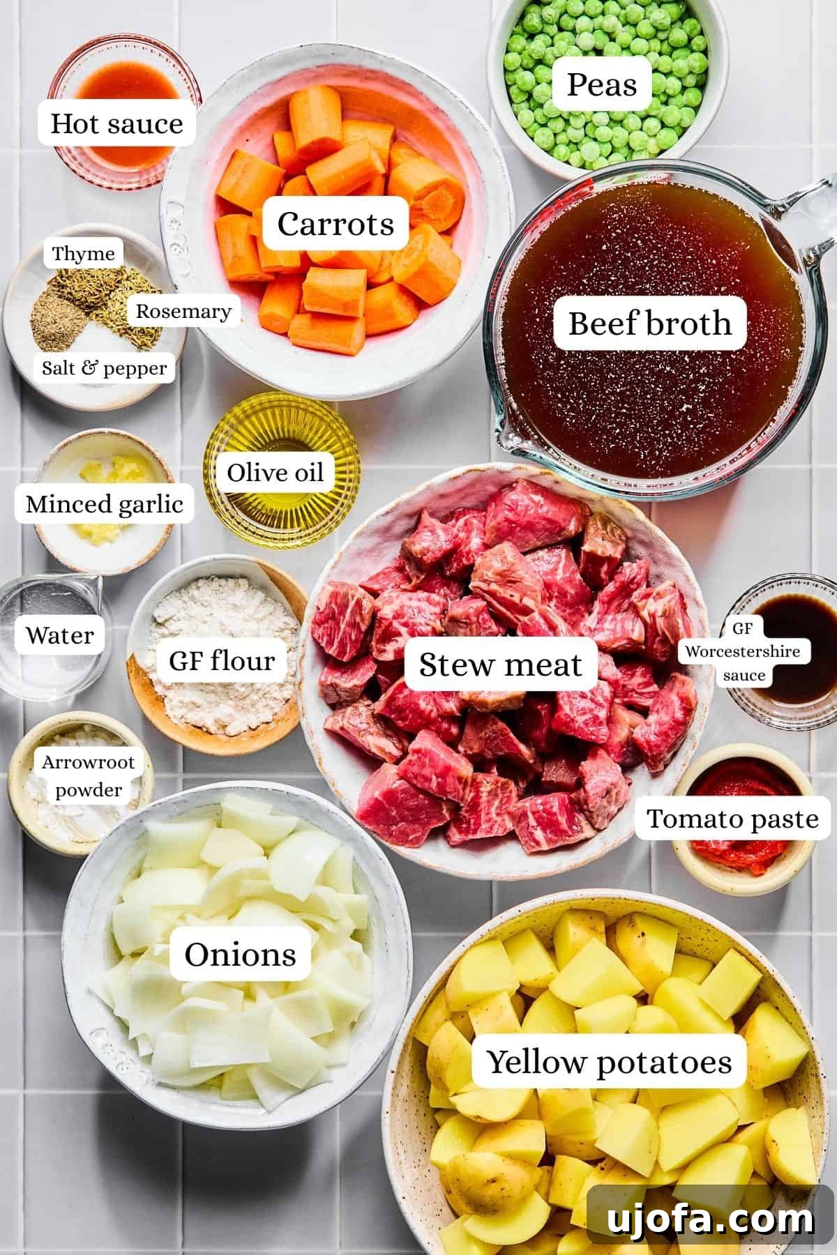 Set It and Forget It Hearty Beef Stew 3 All the fresh ingredients for beef stew, including cubed beef, chopped carrots, potatoes, onions, garlic, and various seasonings, laid out on a white countertop.