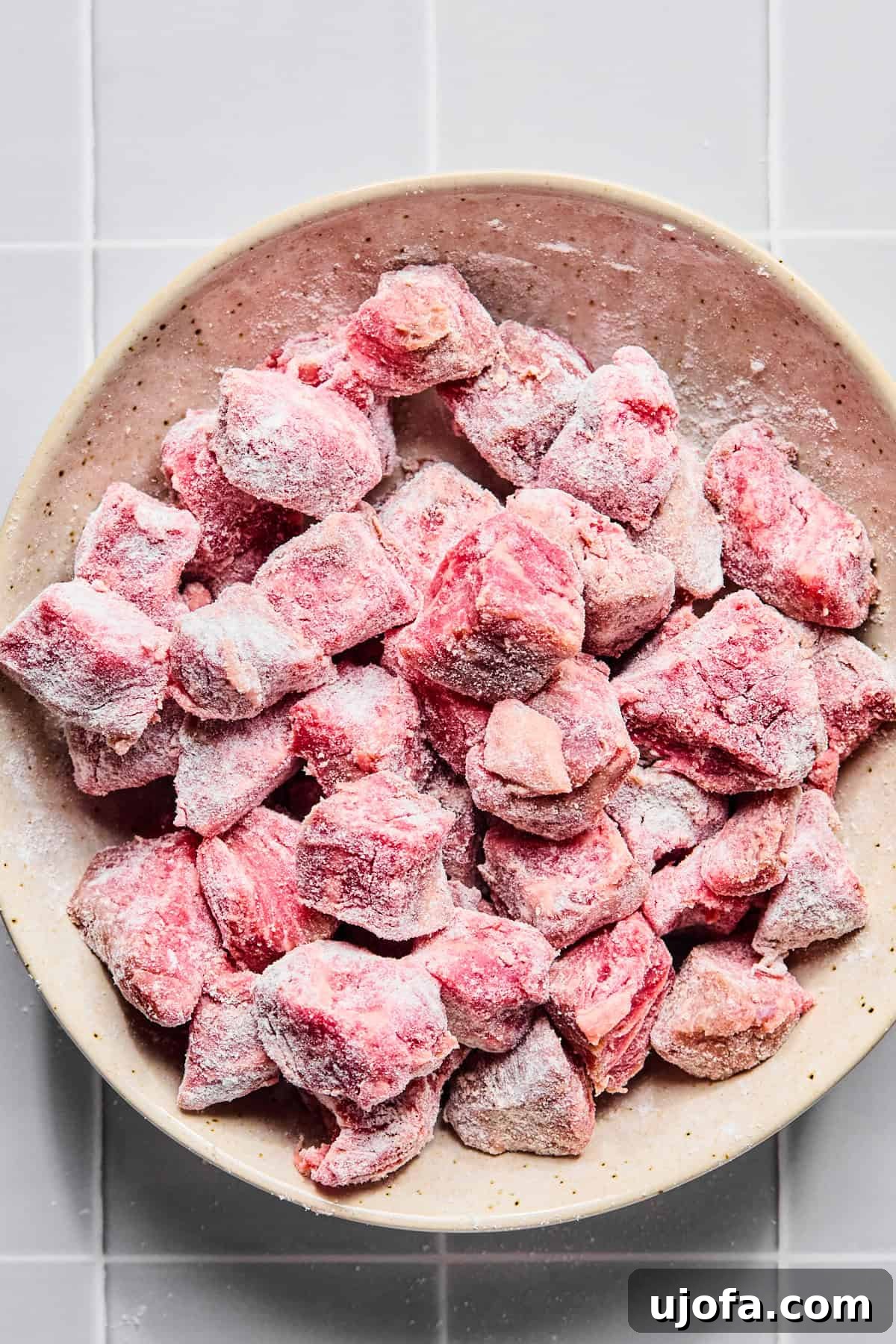 Set It and Forget It Hearty Beef Stew 4 Cubed stew meat coated evenly with gluten-free flour, salt, and pepper in a mixing bowl.