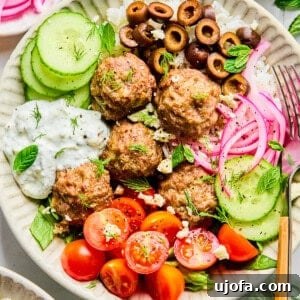 Greek lamb meatballs in a bowl with veggies and lemon dill feta sauce