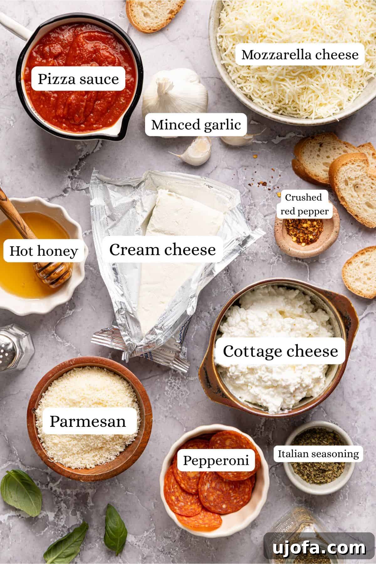 Ultimate Creamy Protein Pizza Dip 3 High protein pizza dip ingredients meticulously labeled and arranged in various nesting bowls on a sleek light gray countertop, perfectly organized and ready for the preparation process.
