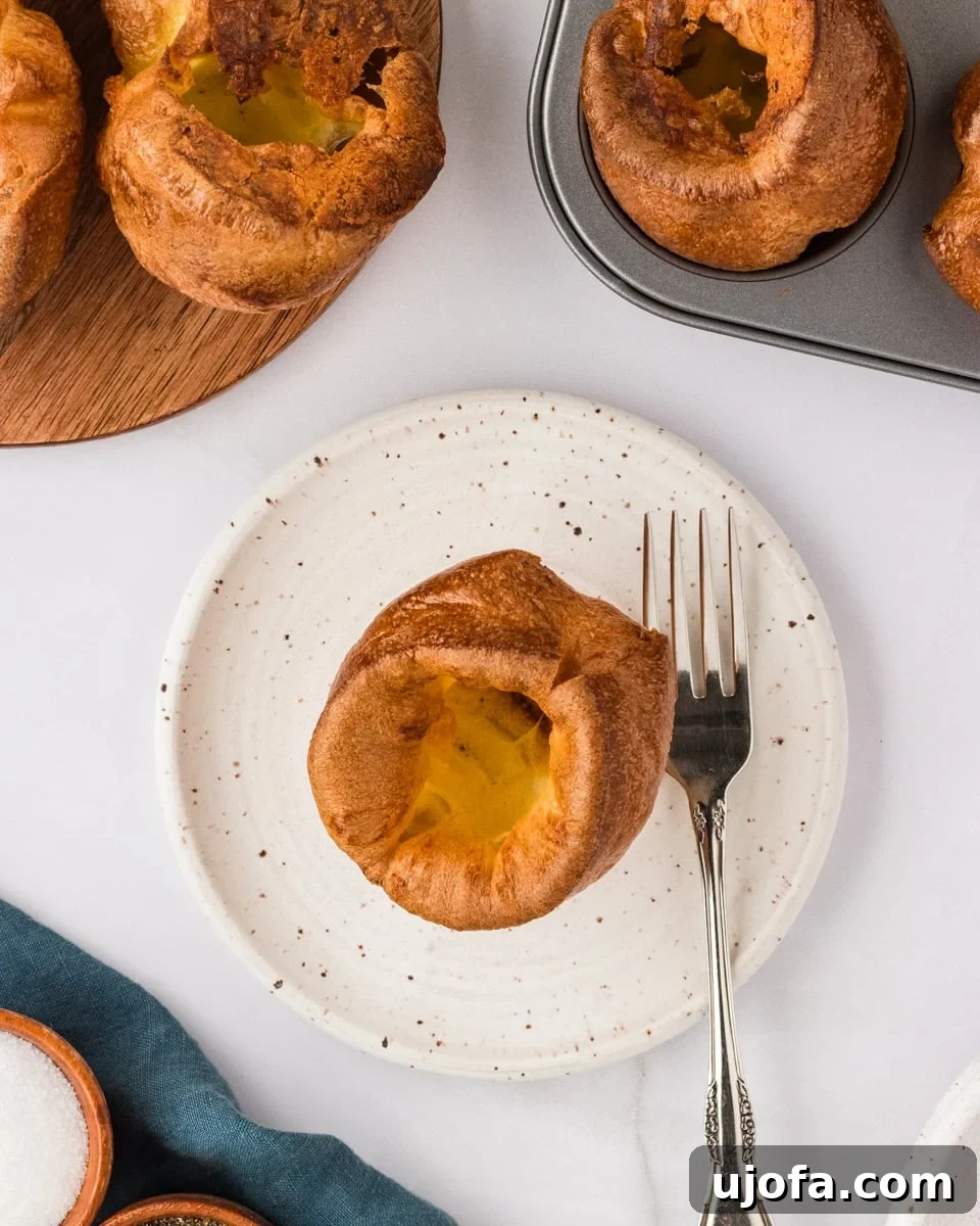 Perfect Gluten-Free Yorkshire Puddings 5 yorkshire pudding on white plate with fork on the side