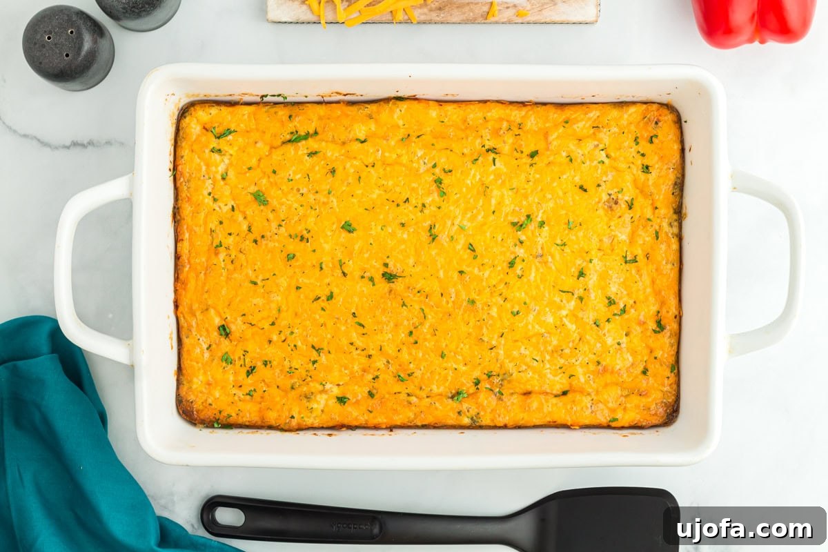 Yuletide Sausage Strata 13 A gloriously golden and bubbly baked breakfast sausage casserole, hot out of the oven in its white baking dish, ready to be served on a festive morning. The cheese topping is melted to perfection, hinting at the savory delight within.