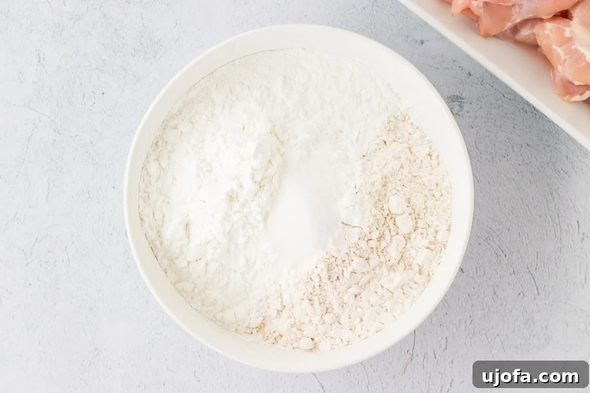 Gluten-free flour and cornstarch mixture in a white bowl, ready for chicken coating.